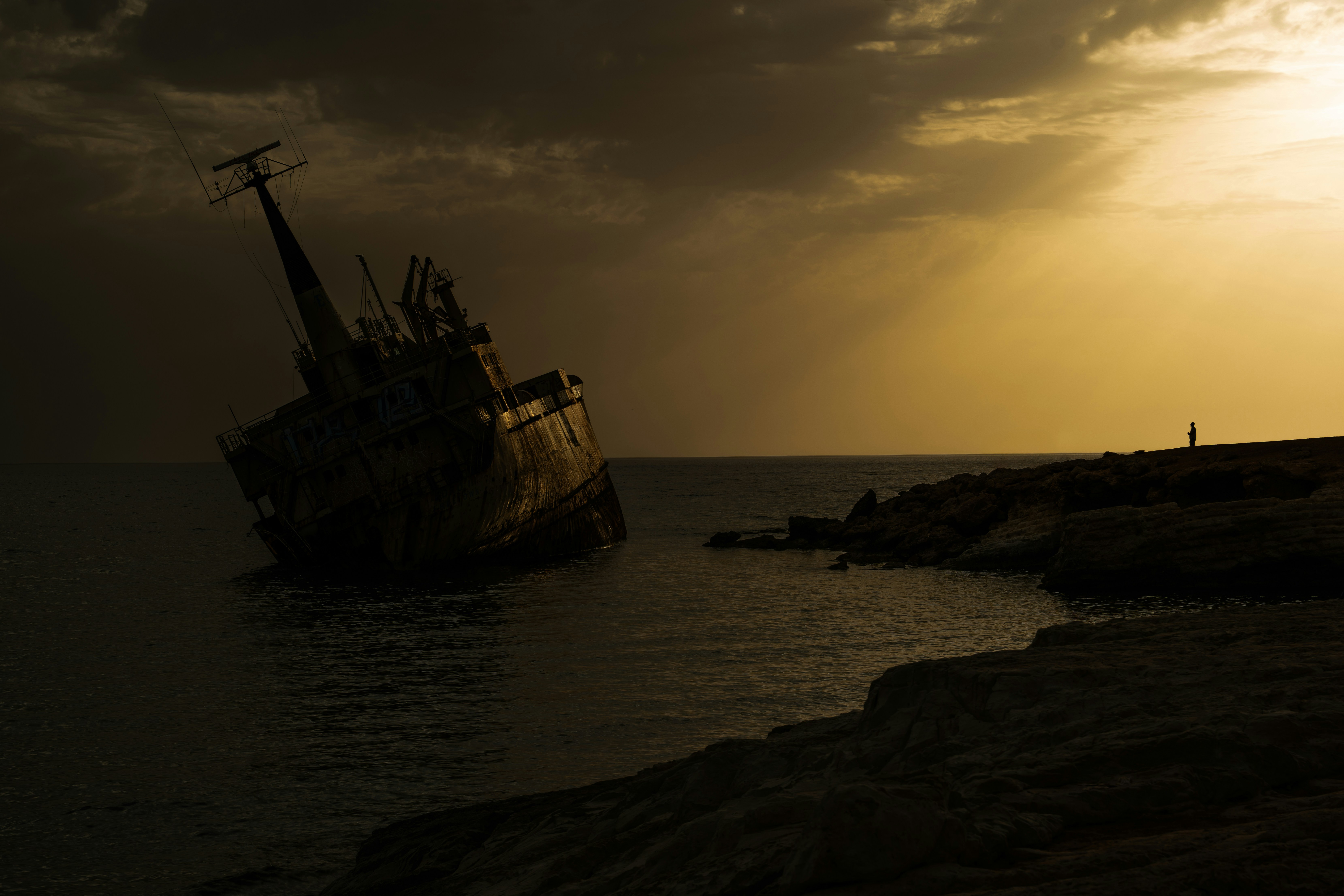 Bei Sonnenuntergang liegt ein Schiffswrack am Ufer.