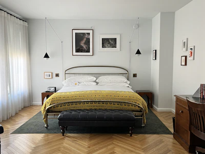 A stylish bedroom with a metal bed and artwork.