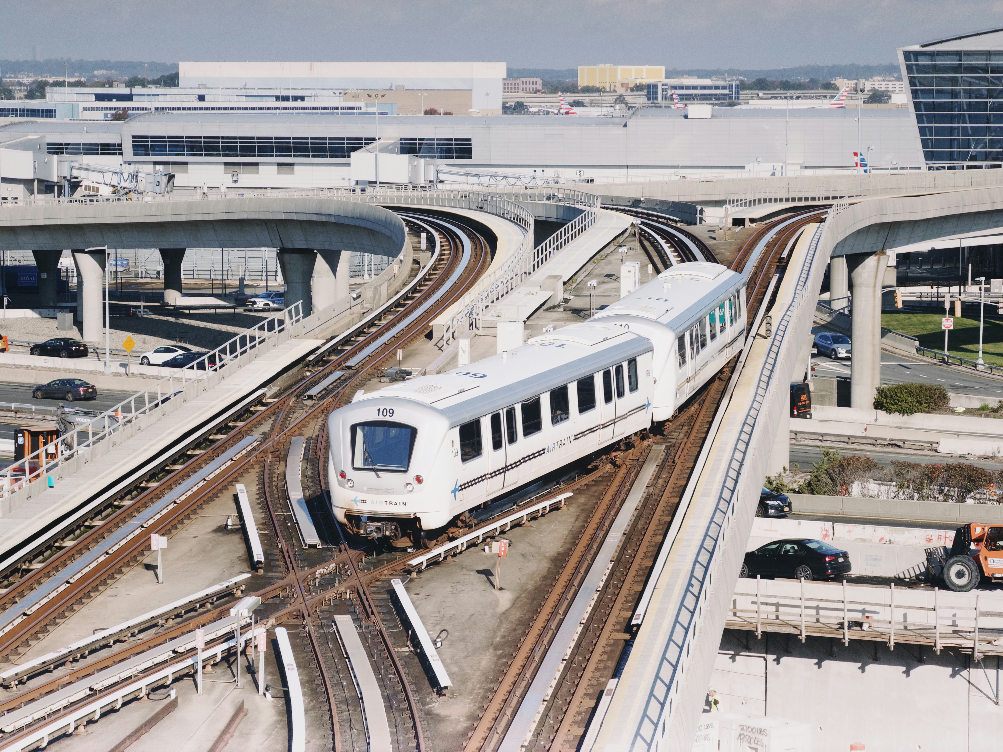 A modern train travels on elevated tracks near airport buildings.
