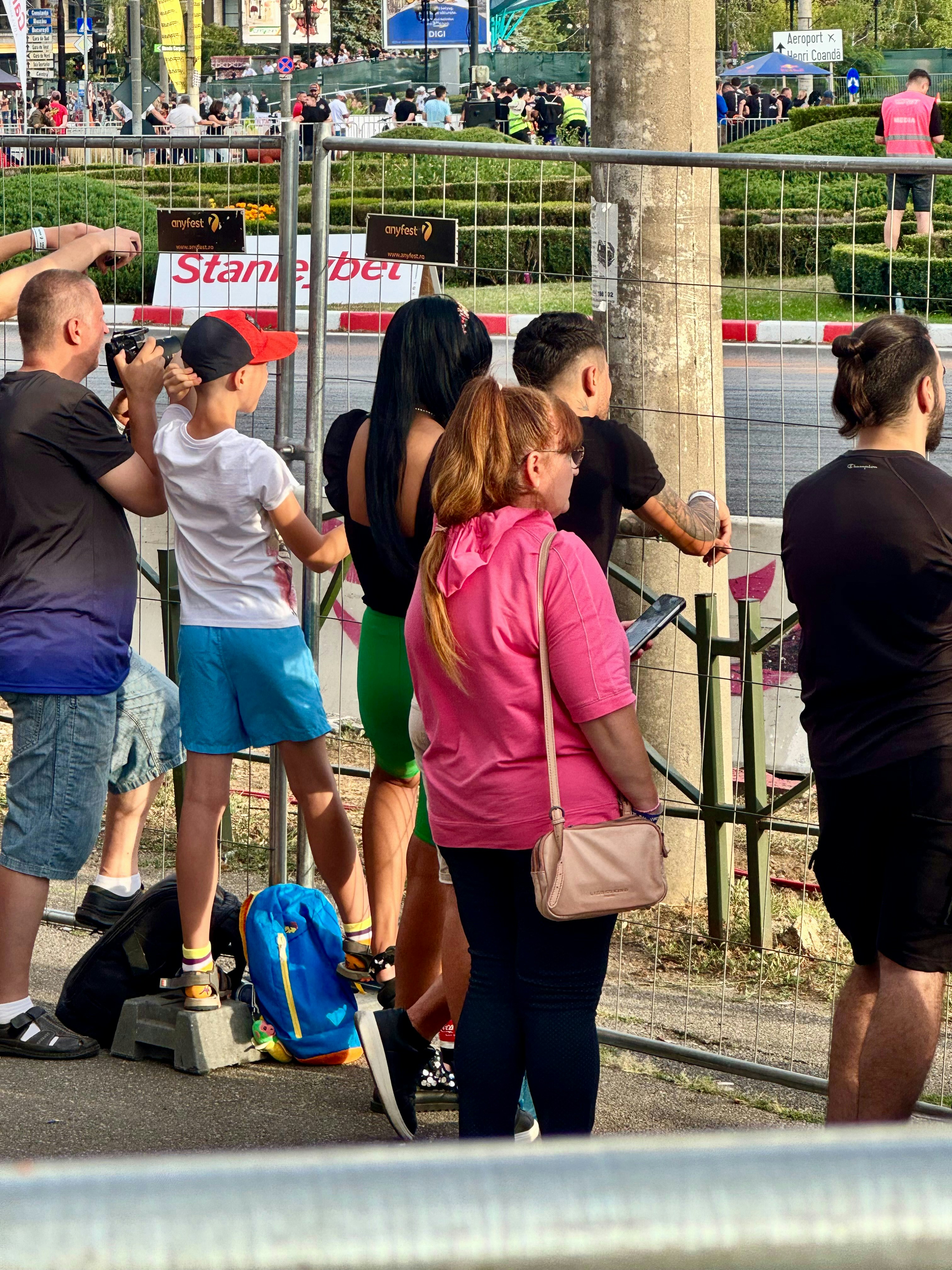 Gente viendo un evento de carrera detrás de una cerca.