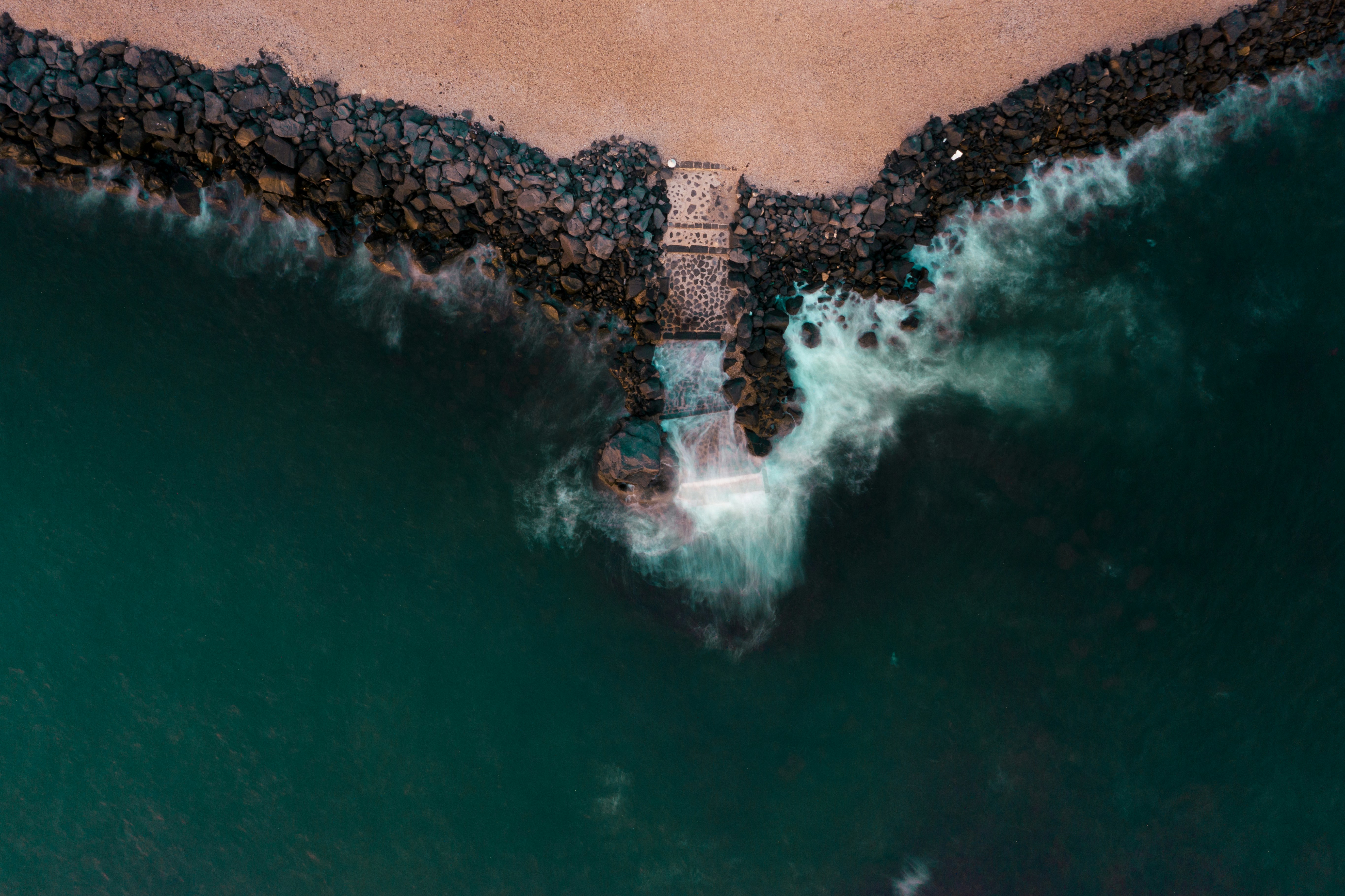 Waves crashing against a rocky pier at sea.