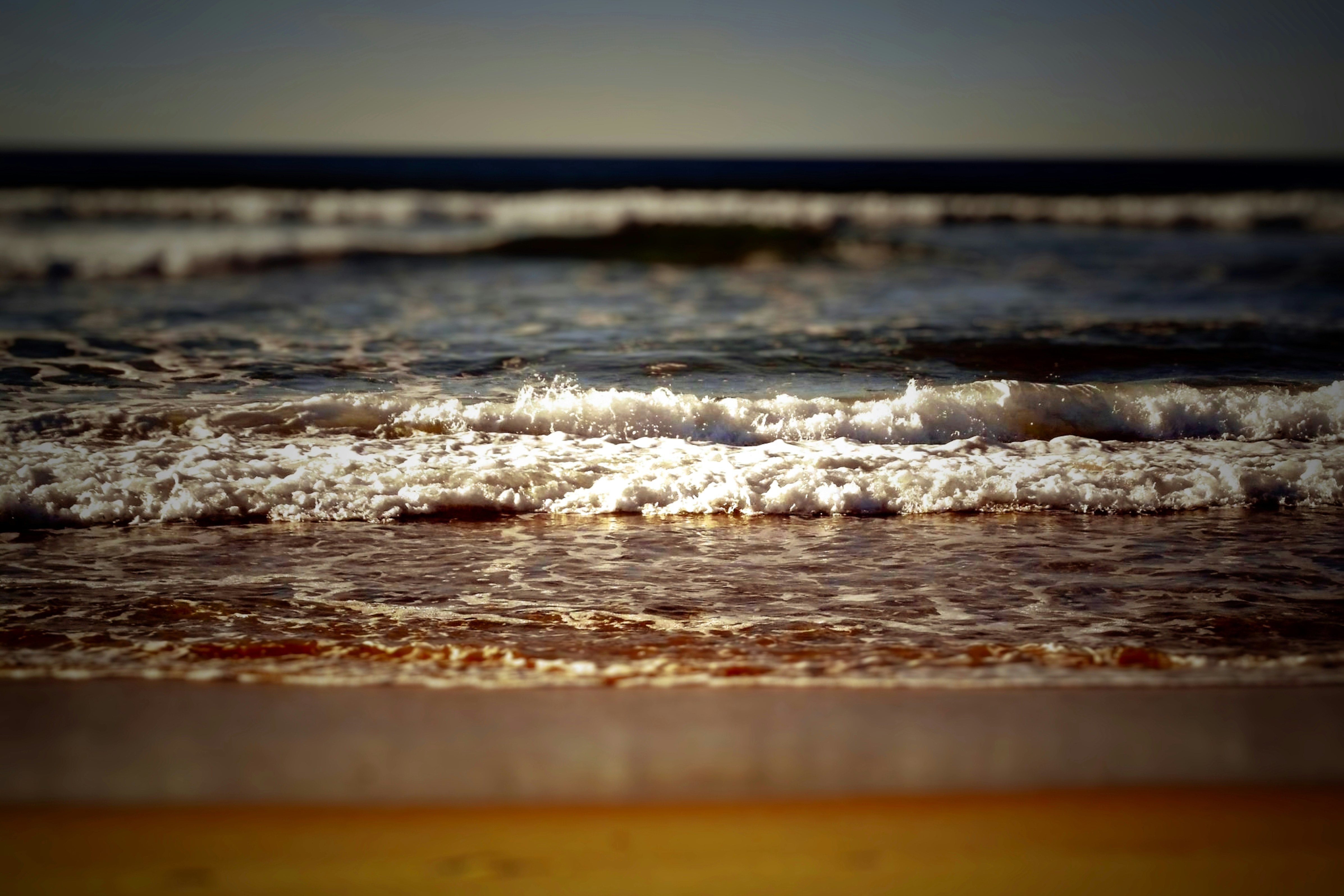 Waves gently crashing on a sandy beach.