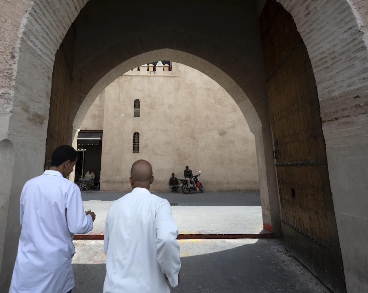 Two people walking through a traditional archway in Marrakech's medina