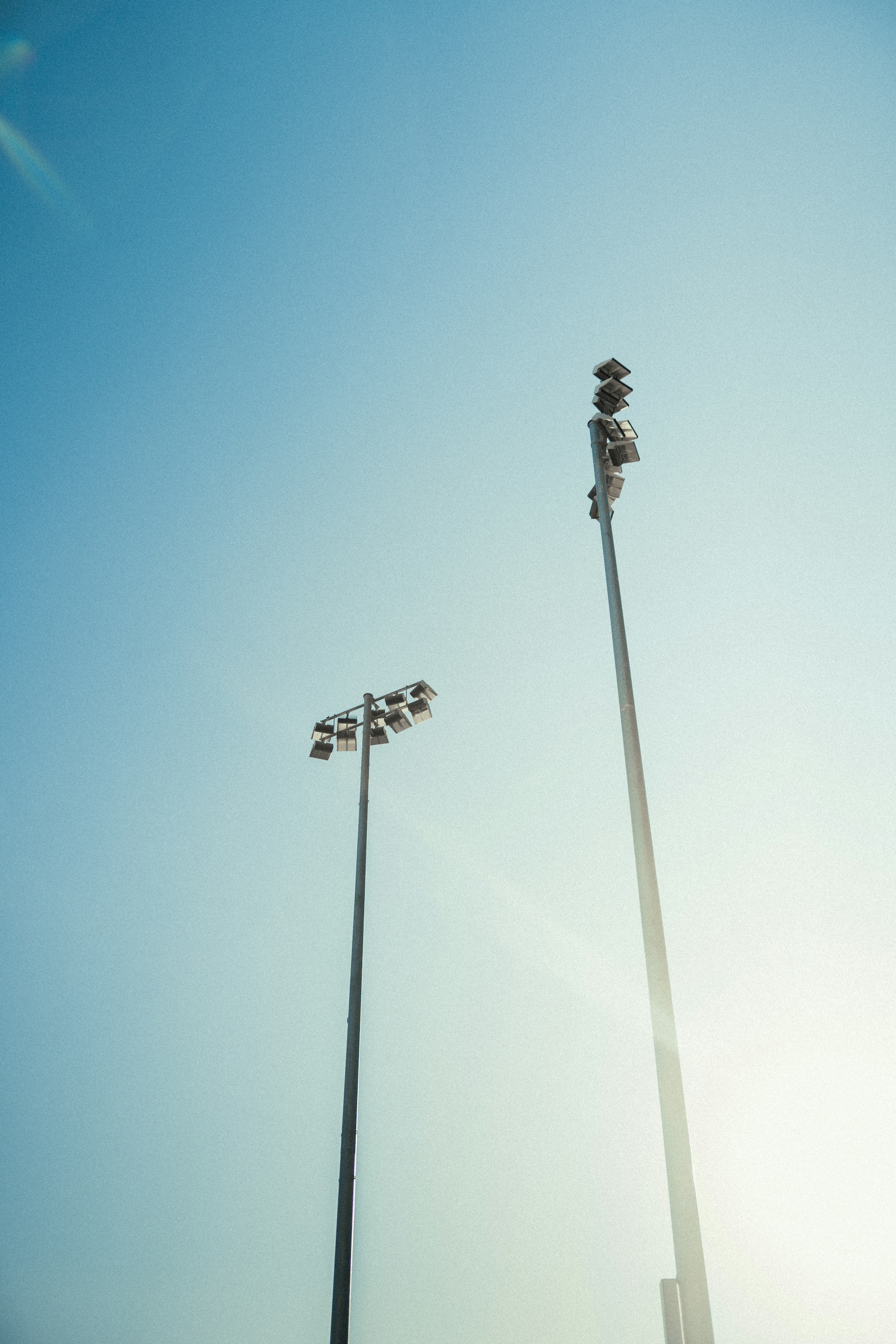 Two tall light poles against a clear blue sky
