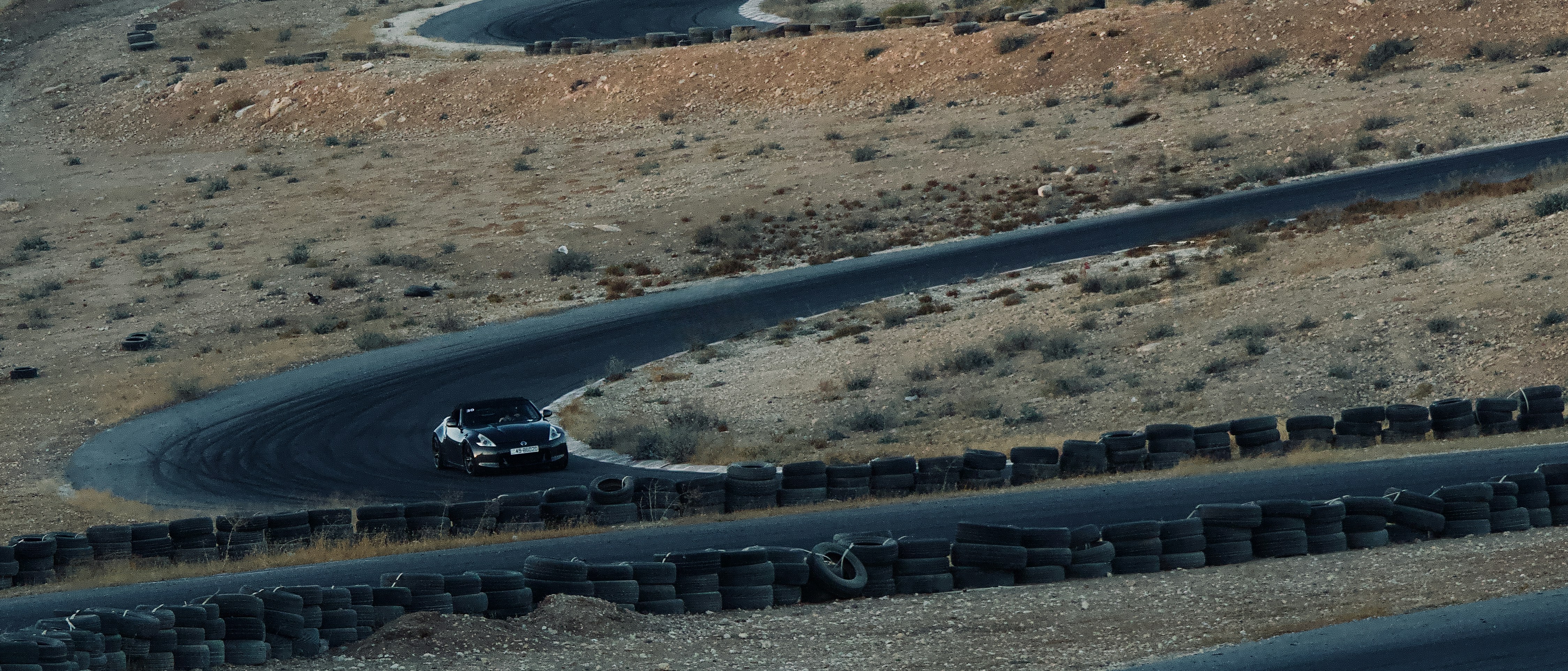 Car driving on a winding race track in desert.