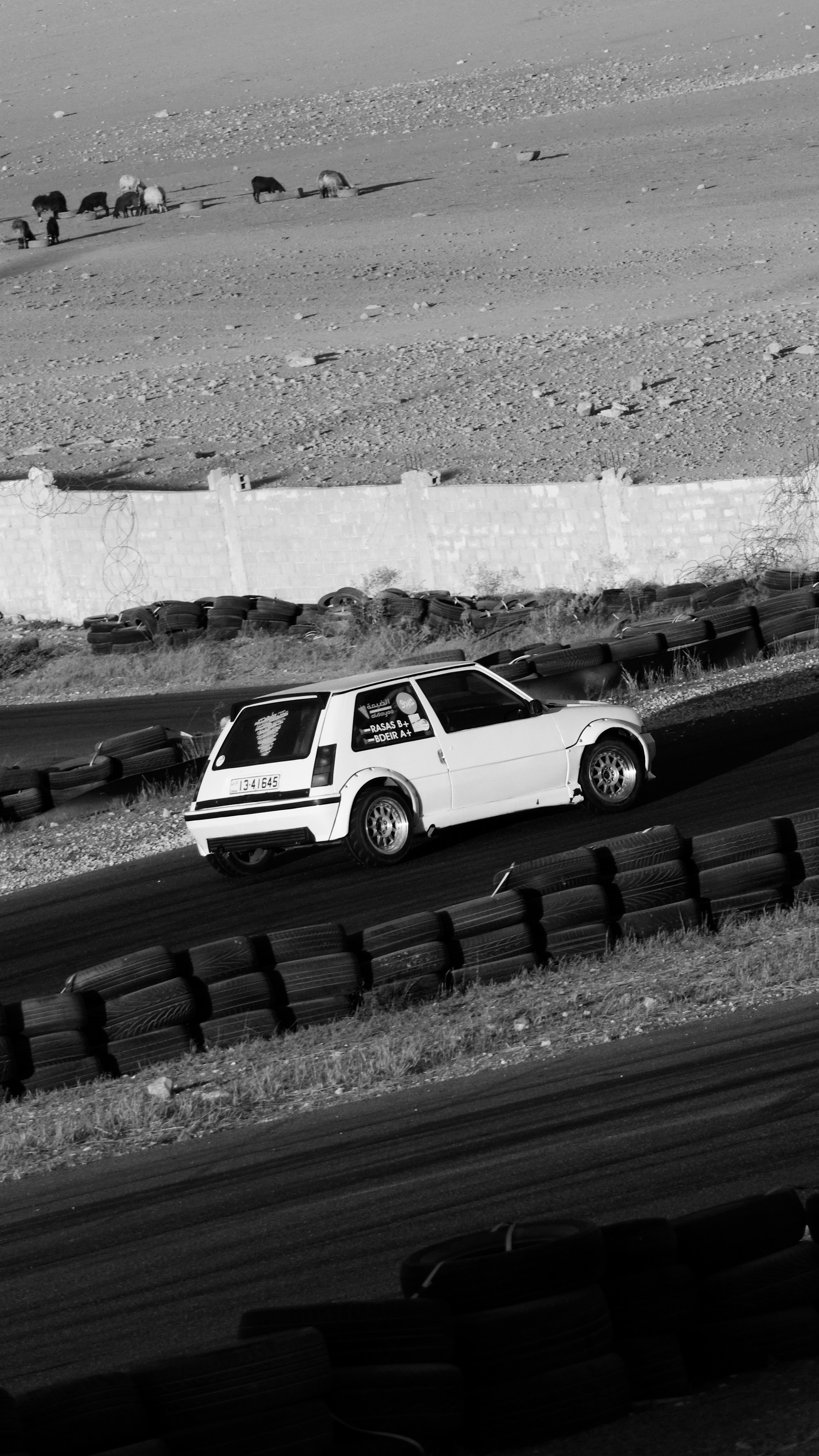 White race car on a track with tire barriers
