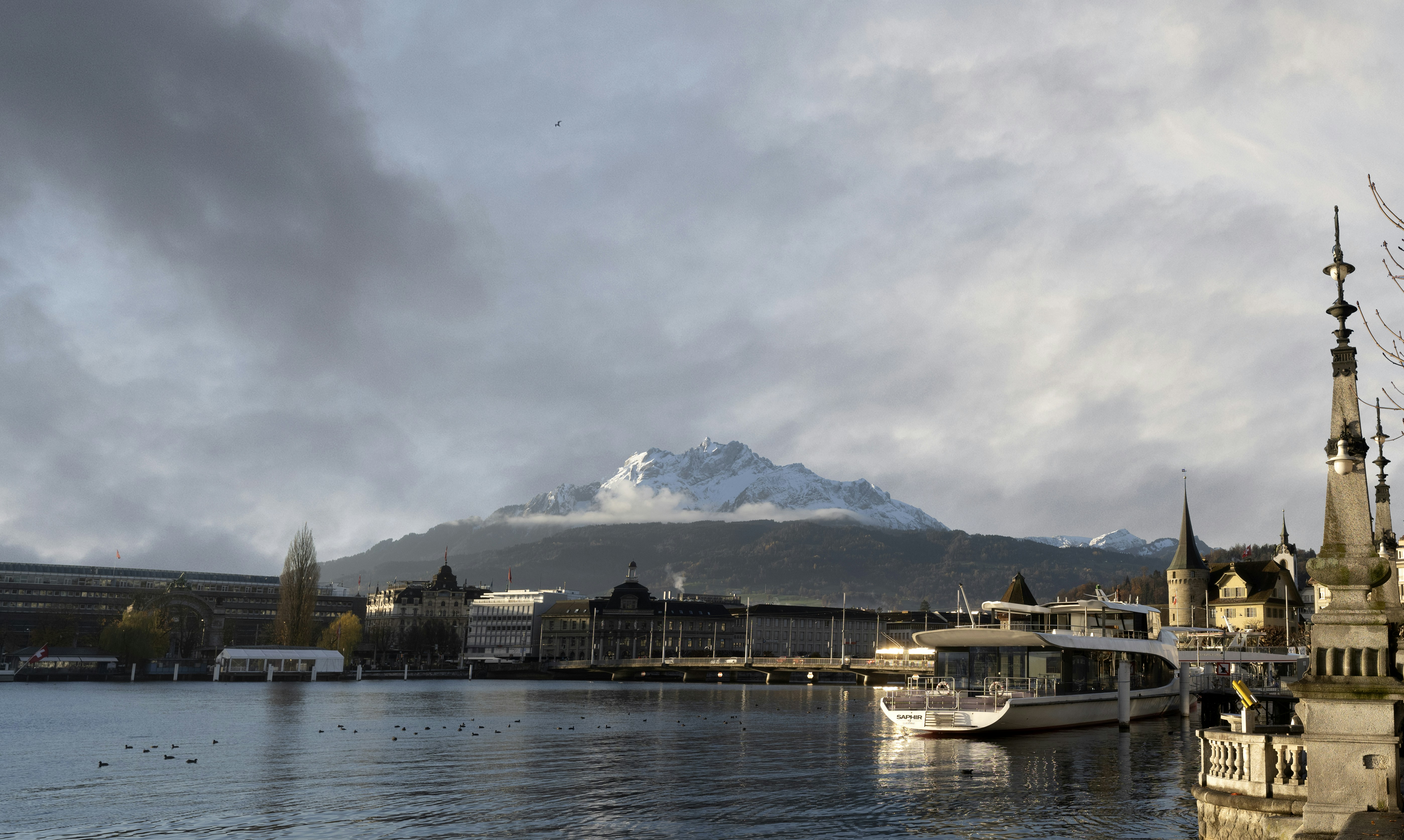 جبل مغطى بالثلوج يطل على بحيرة سويسرية بها مبانٍ وقارب