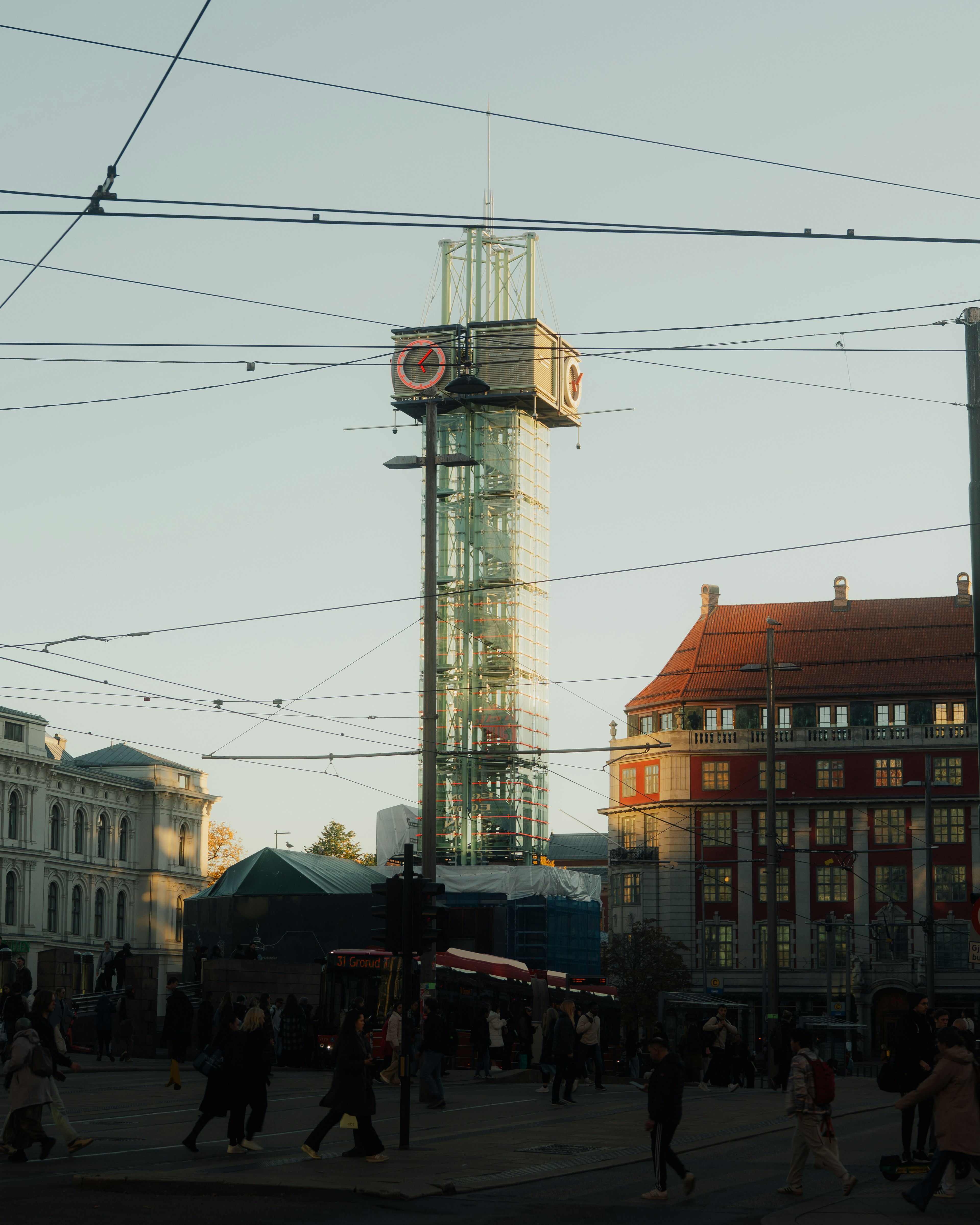 Modern glass tower with clock above bustling city square