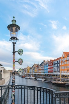 Colorful buildings line a canal with boats and lamp post.