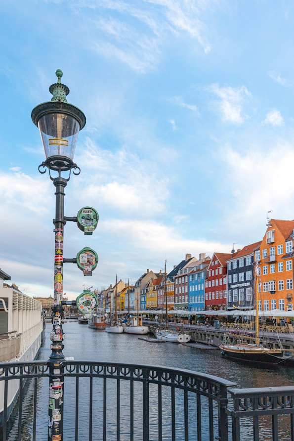Colorful buildings line a canal with boats and lamp post.
