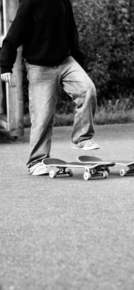 Person standing on two skateboards outdoors.