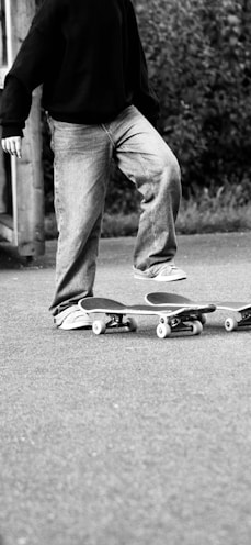 Person standing on two skateboards outdoors.