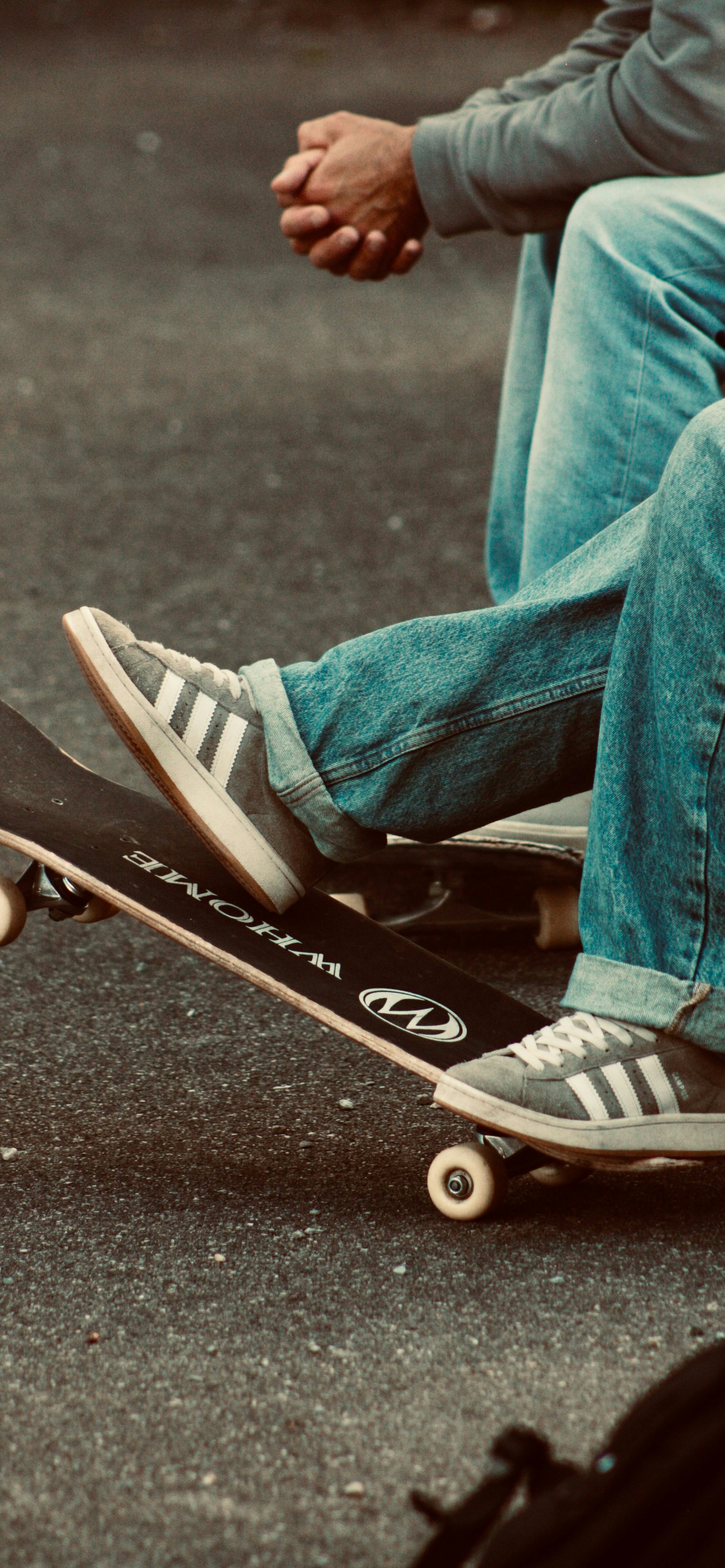 Two people with skateboards on asphalt
