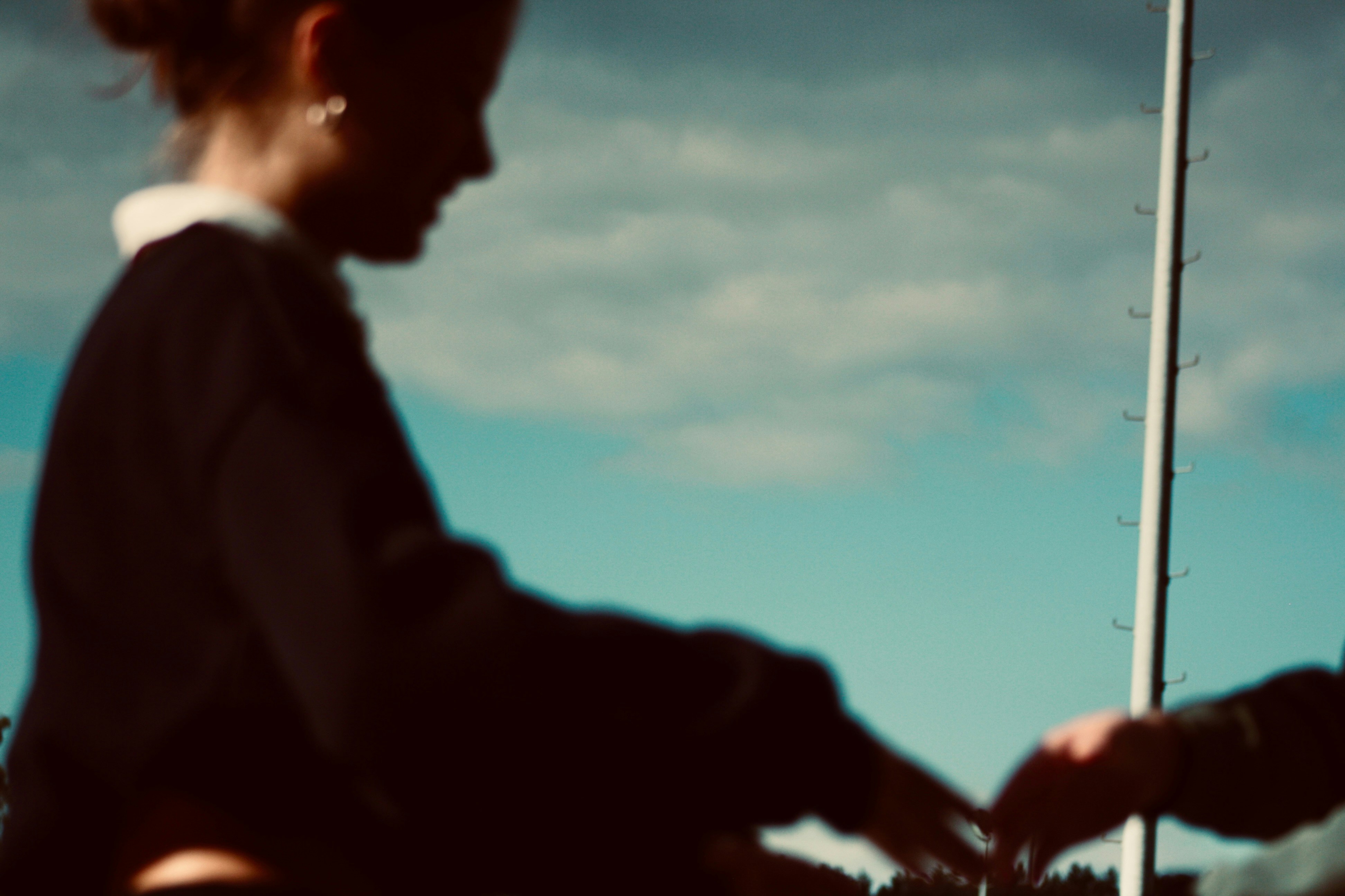 Young woman reaching for something against a cloudy sky