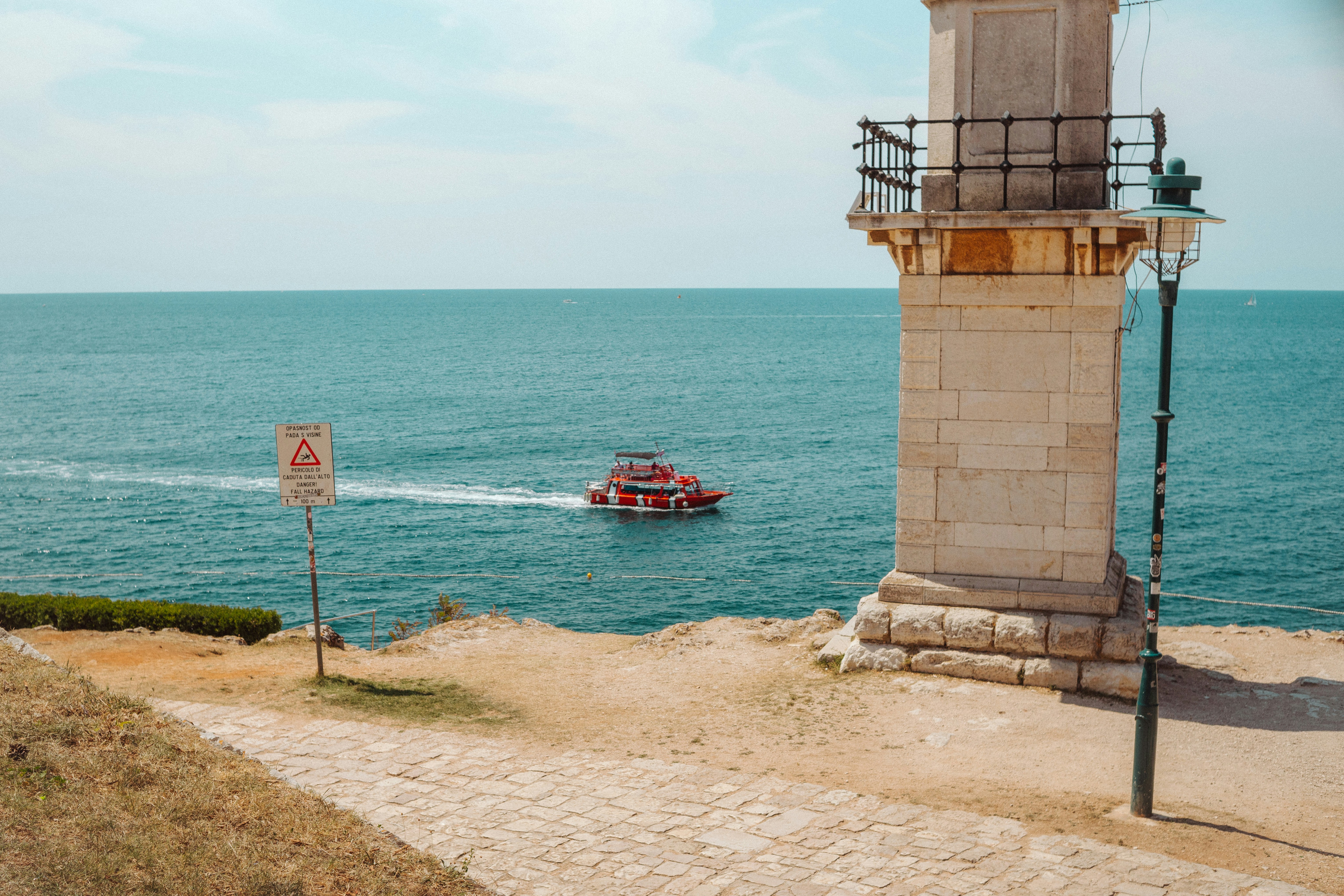 Boat sails past lighthouse on sunny day