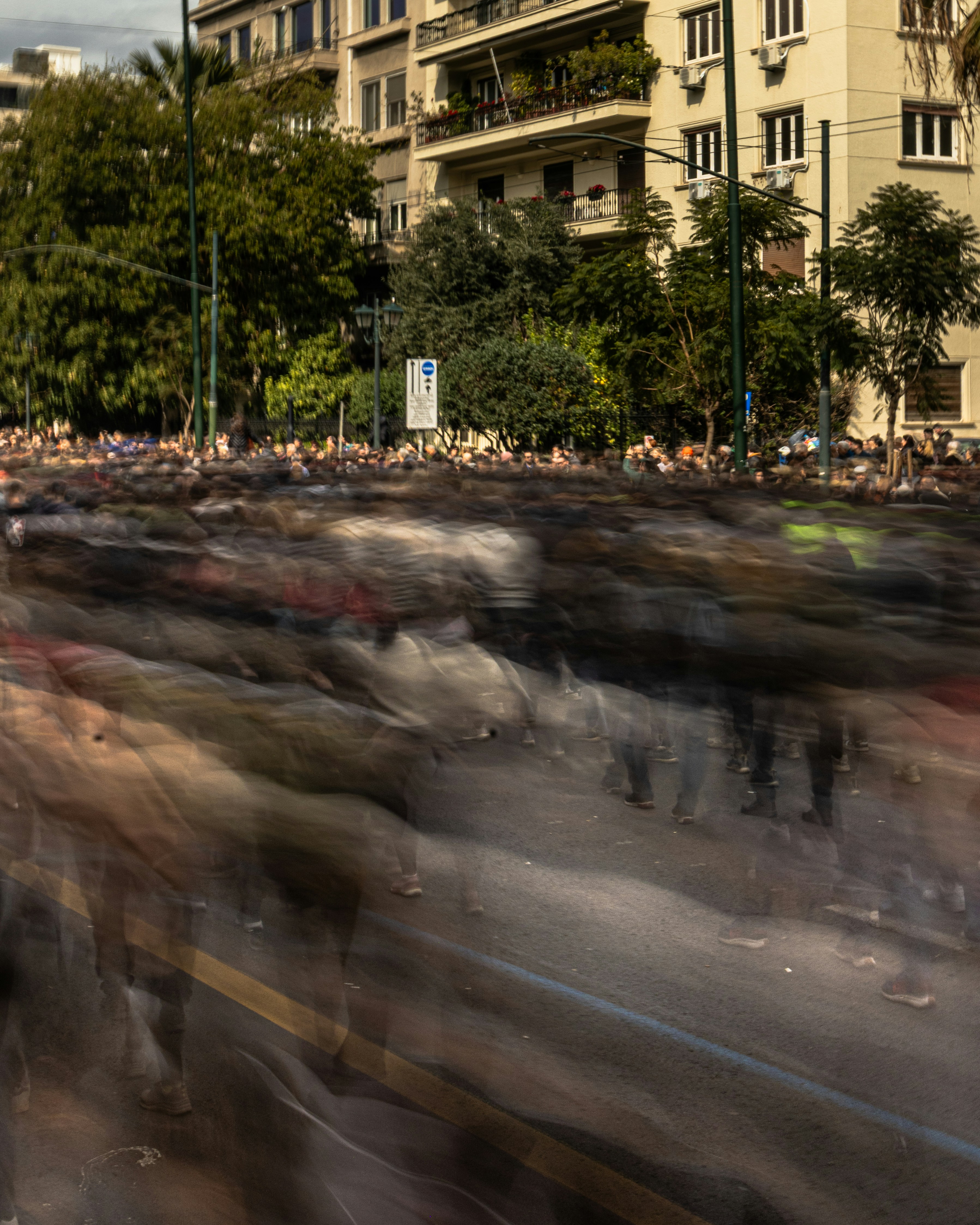Blurred crowd of people moving along a street.