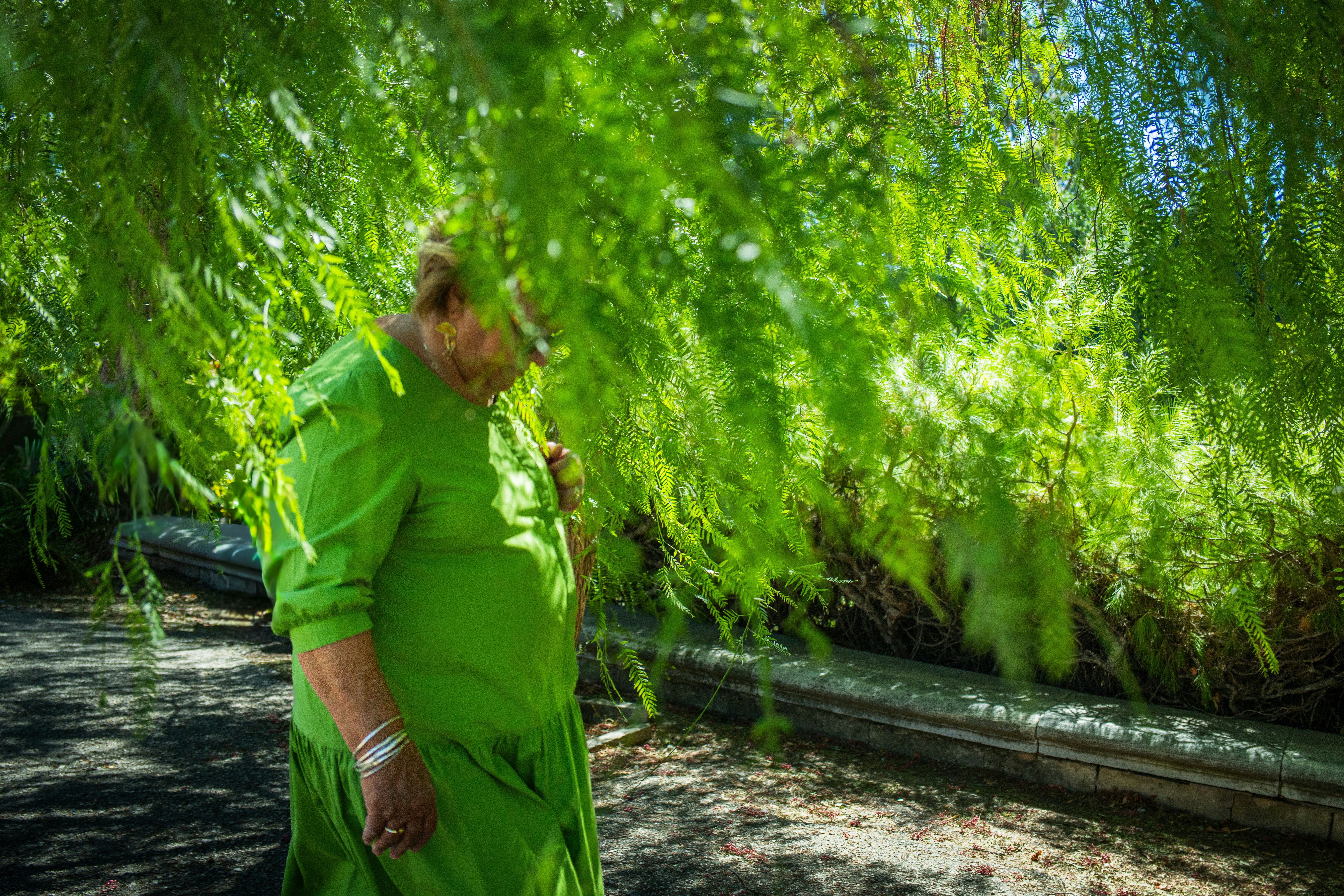 Woman in green dress behind lush green foliage