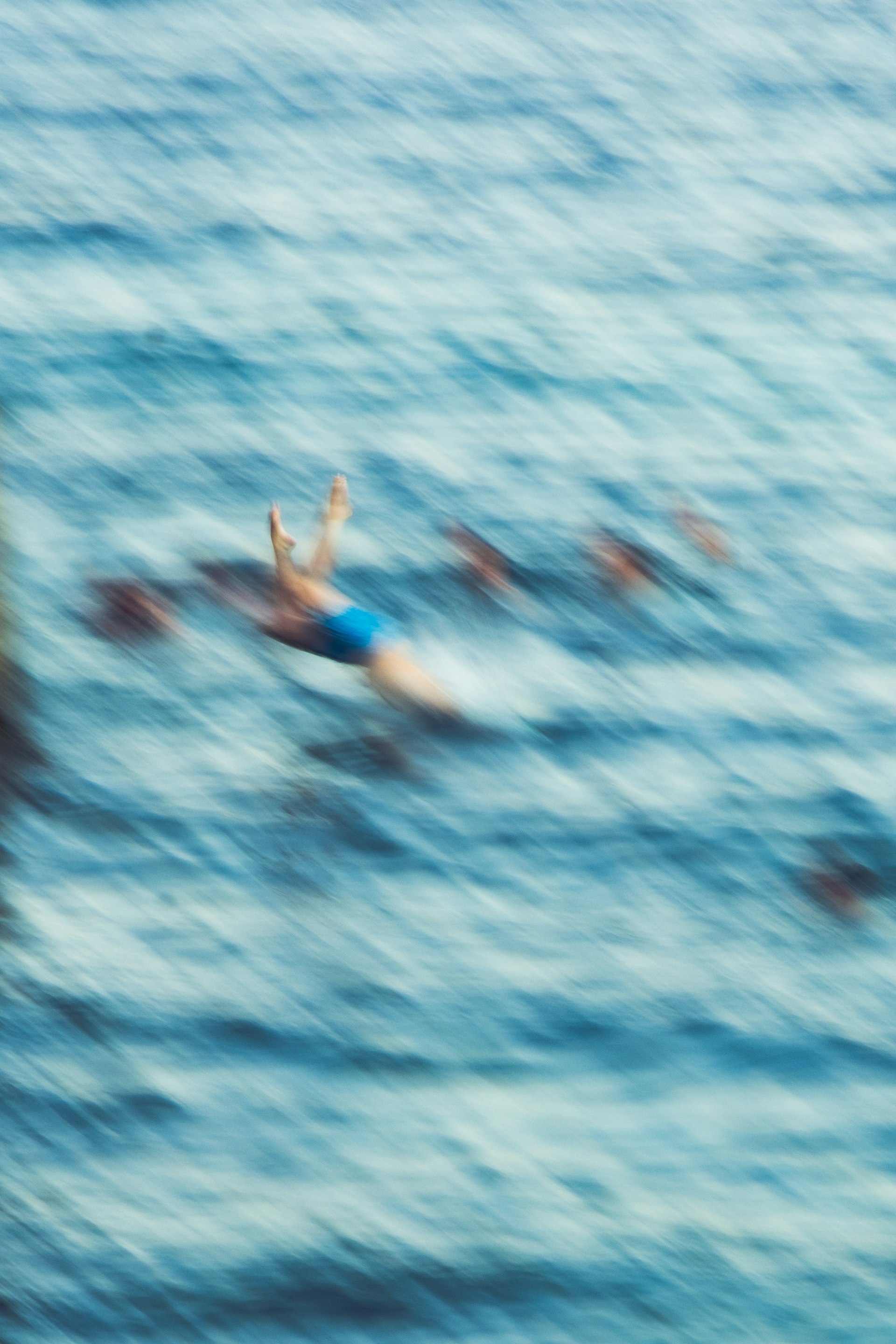 A swimmer mid-stroke in blue water, caught with motion blur.