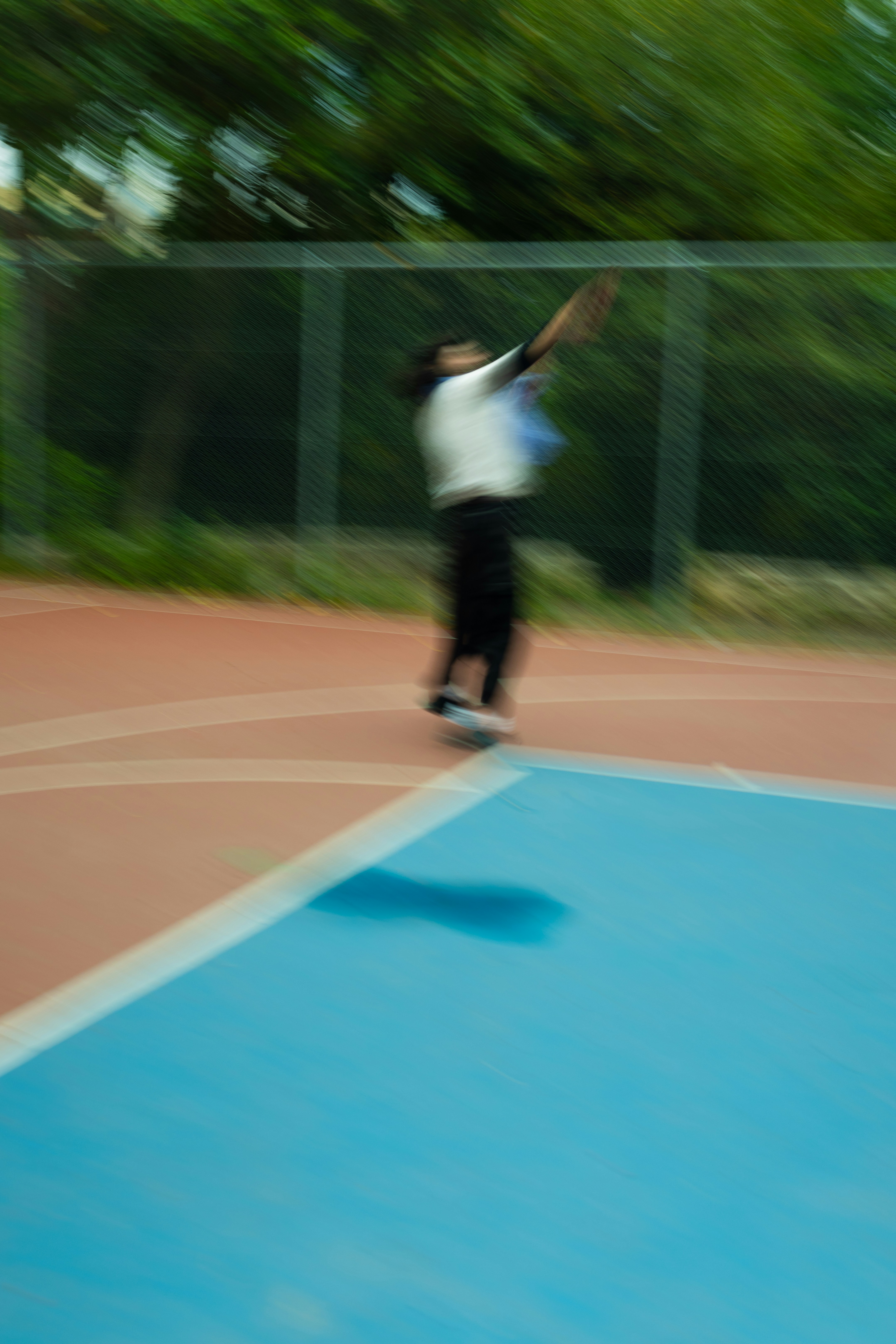 Persona jugando al tenis en una cancha azul y roja.