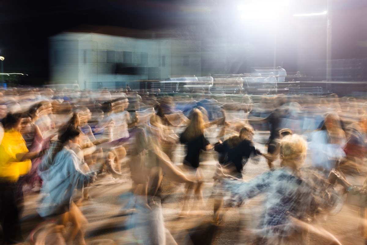 Blurred-motion photograph of people dancing at night, rite-of-passage / ritual register
