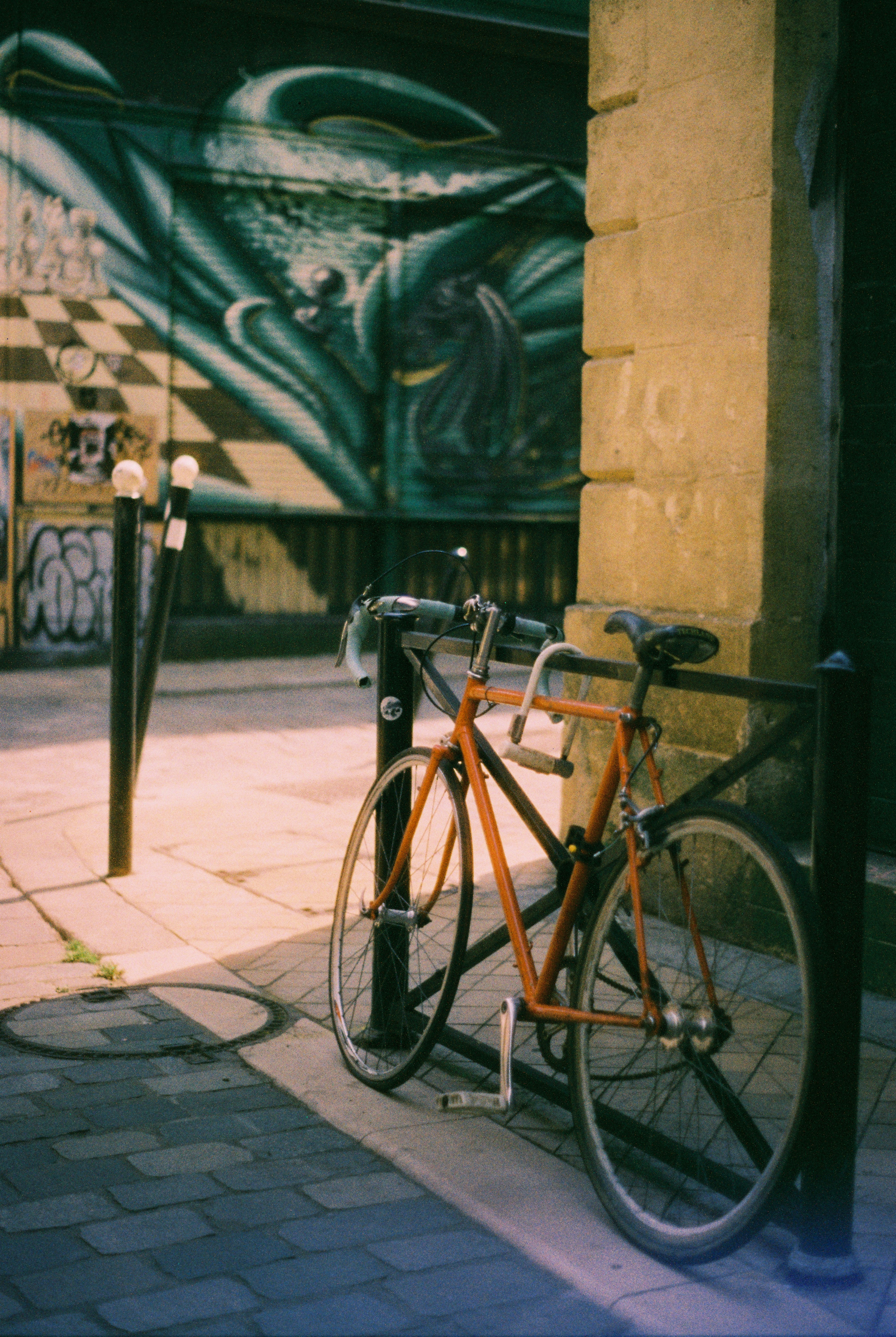 Orange bicycle parked near graffiti wall.