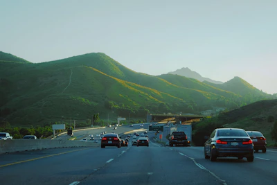 Cars driving on a highway with green mountains.