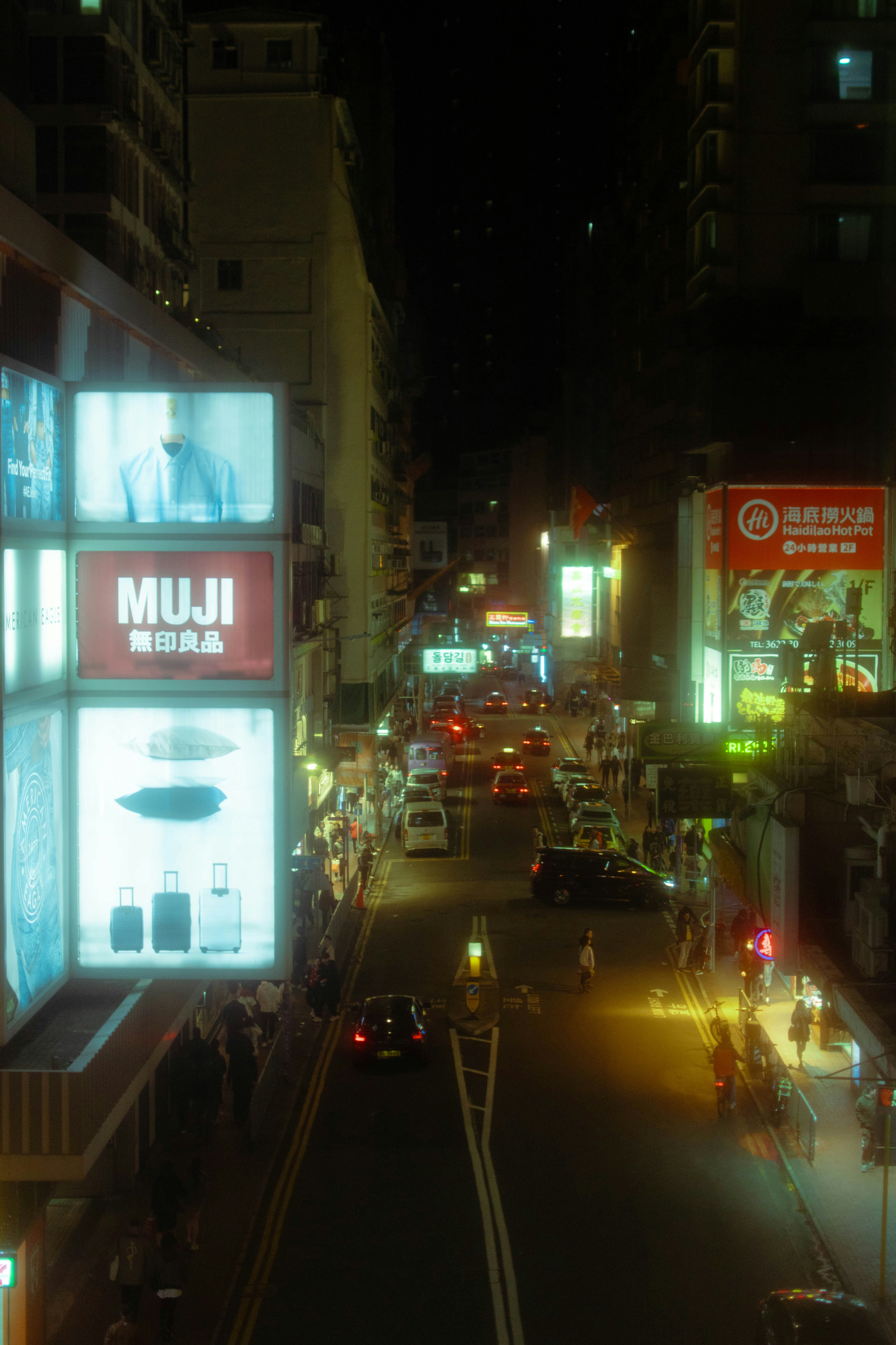 Busy city street at night with bright neon signs.