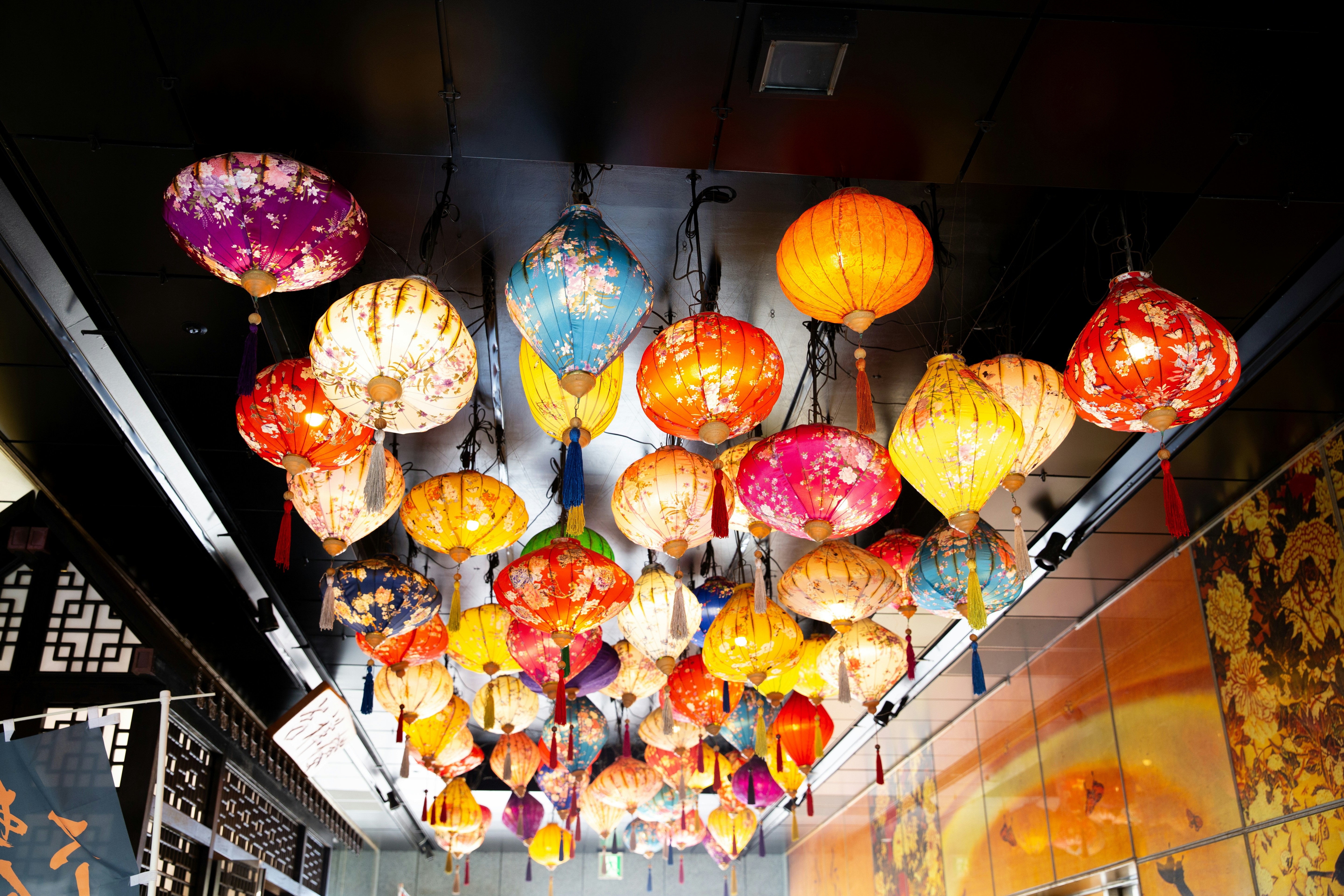Colorful lanterns hanging from a ceiling indoors.