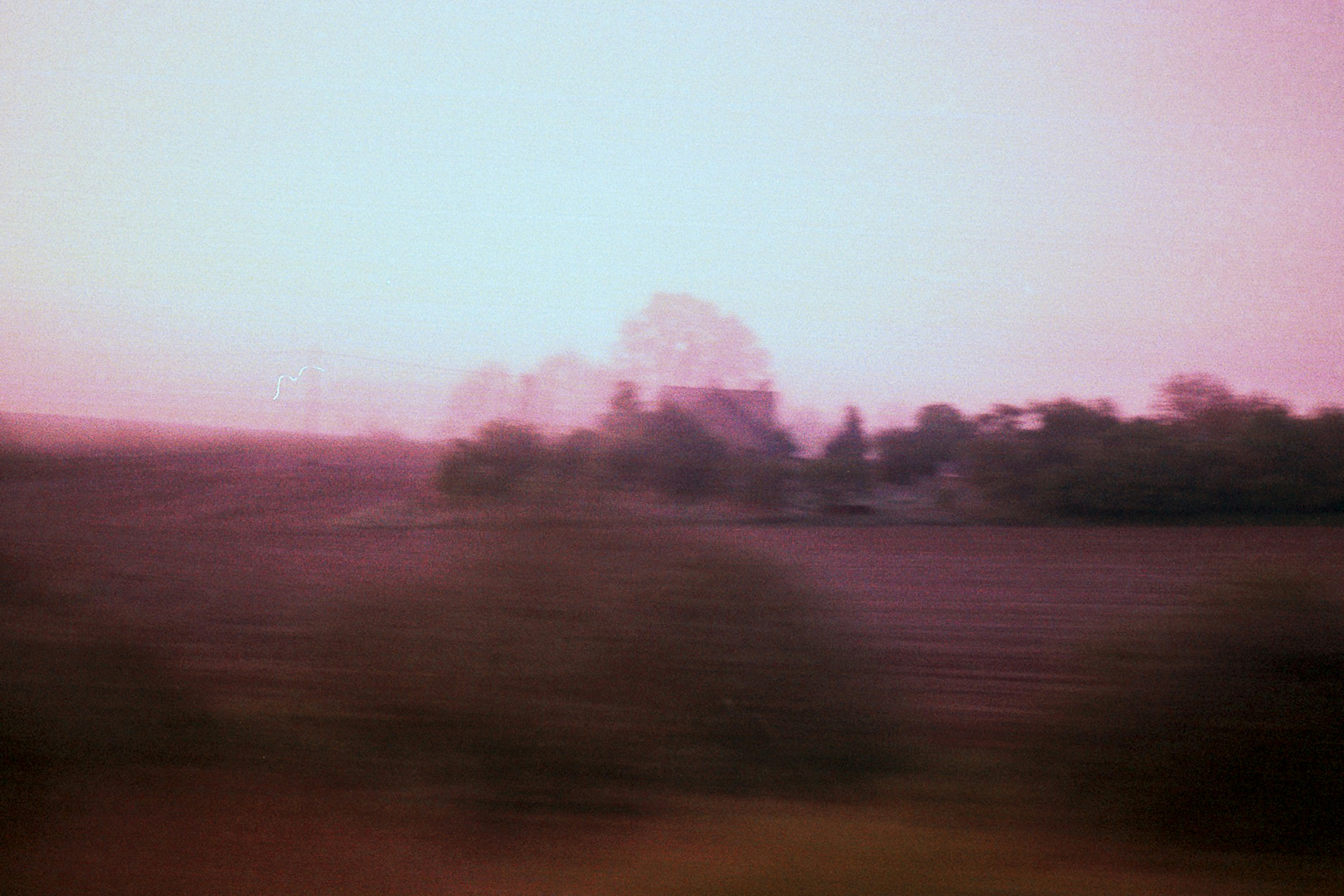 Blurred rural landscape with trees and fields at dusk