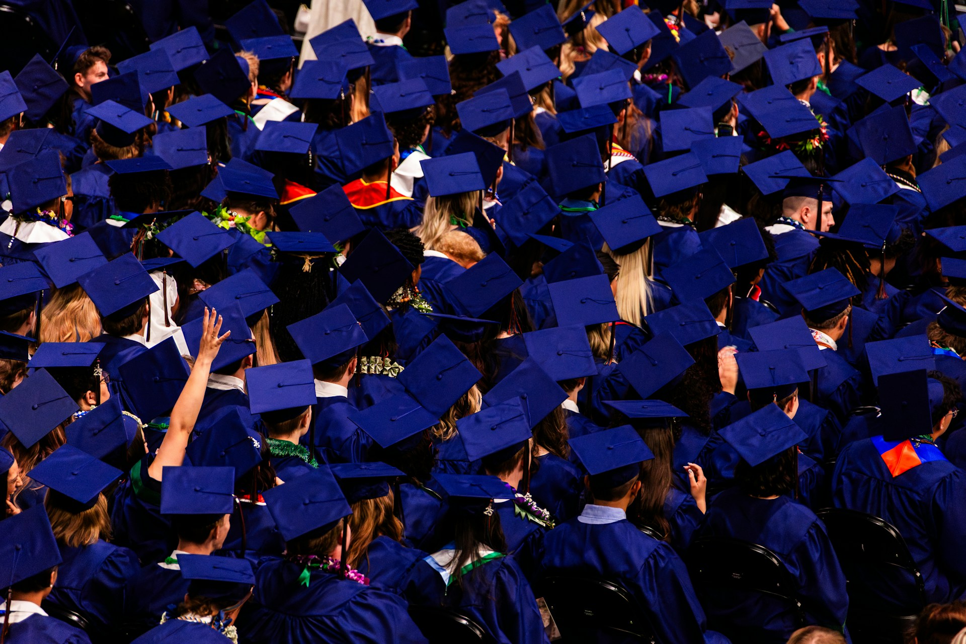 Graduation ceremony with students in blue caps and gowns.