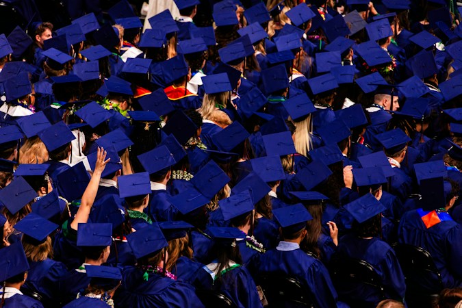 University graduates in blue caps and gowns at a commencement ceremony