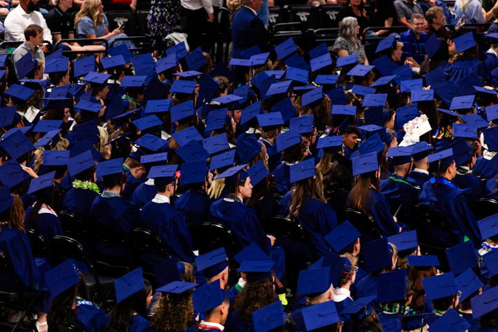 Graduates in blue caps and gowns sitting together