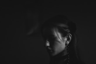 Woman's profile in dramatic black and white lighting.
