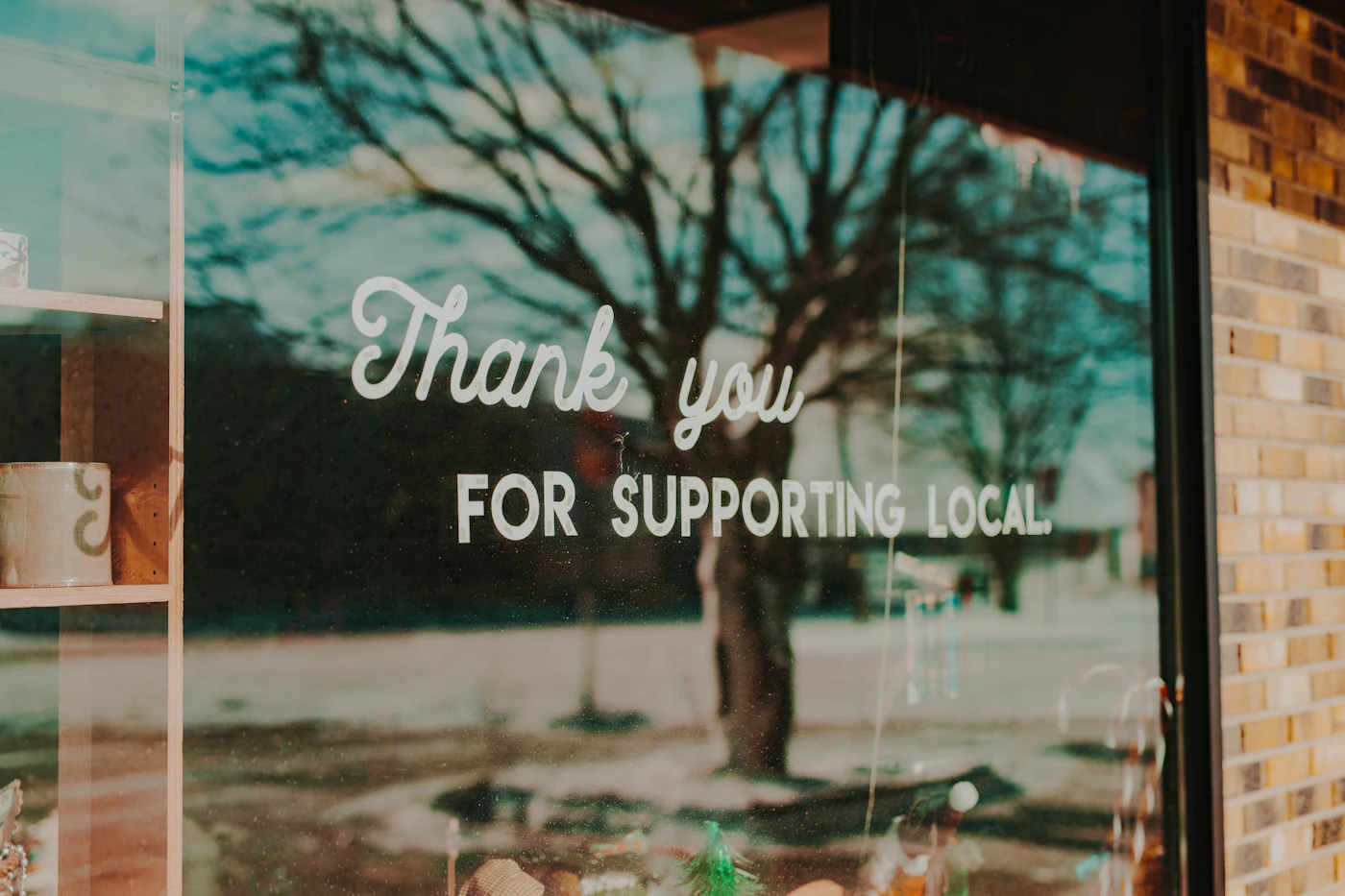 A Thank you for supporting local sign in the window of a neighborhood shop