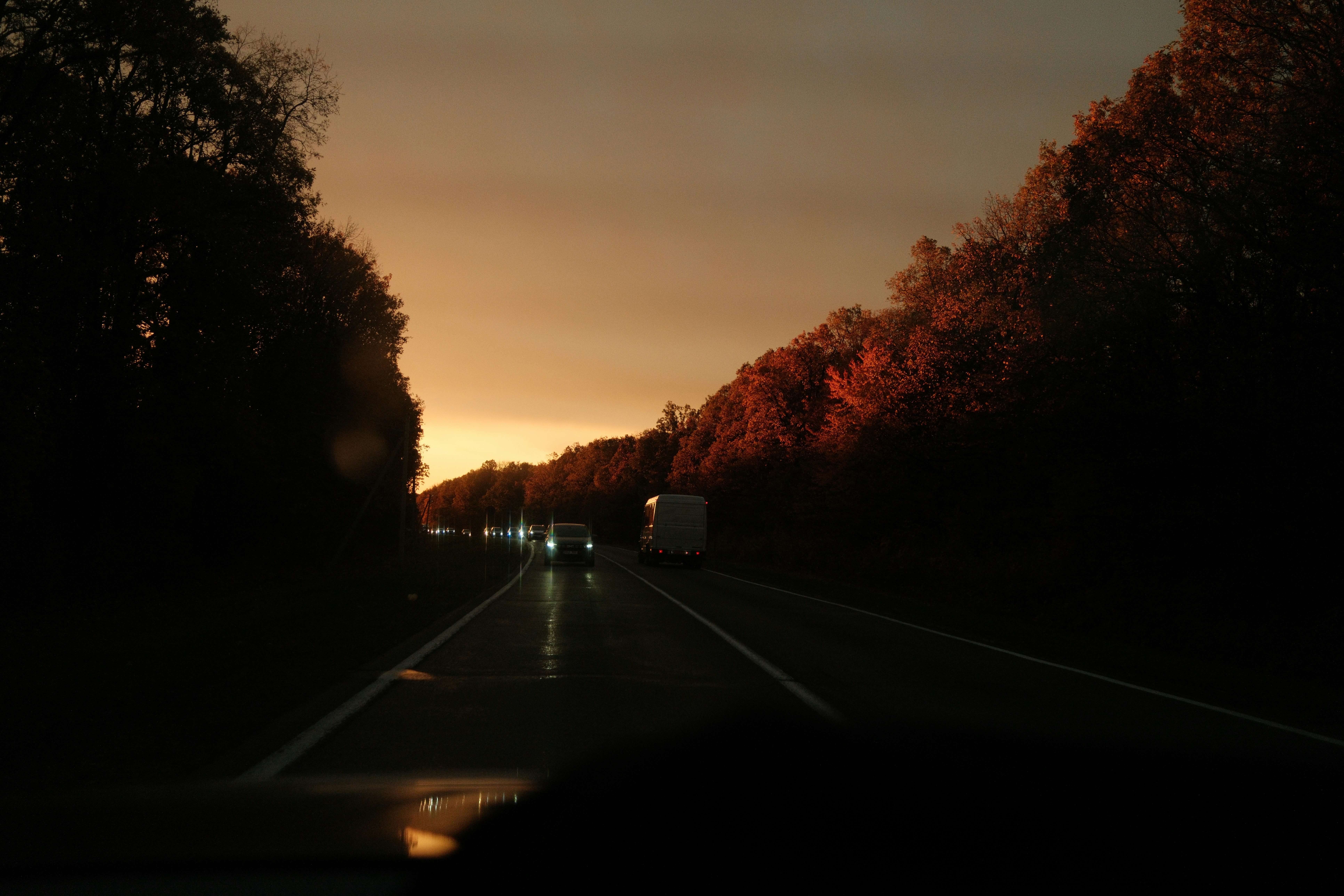 Cars driving on a road at sunset
