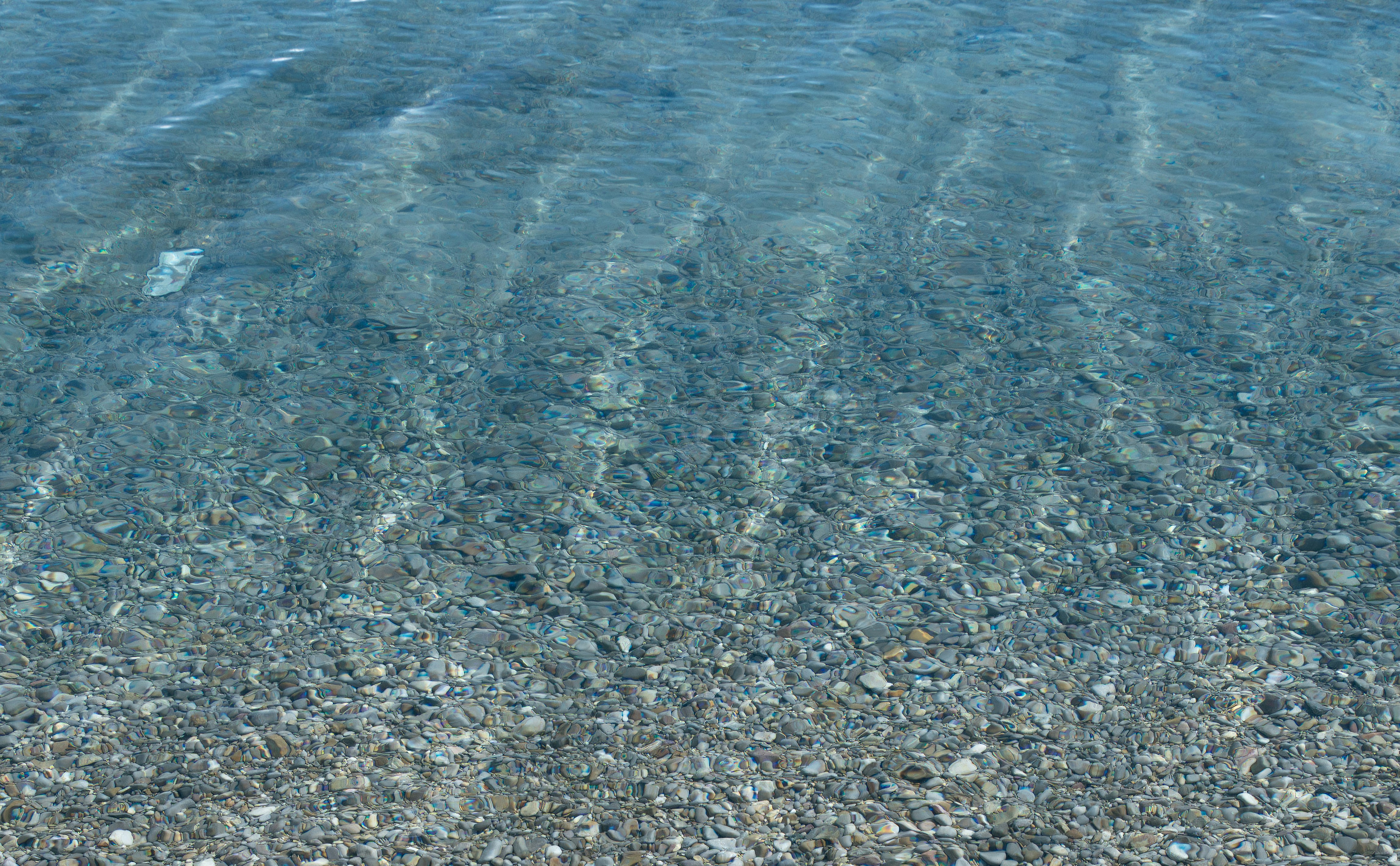 Clear ocean water over a pebble beach.