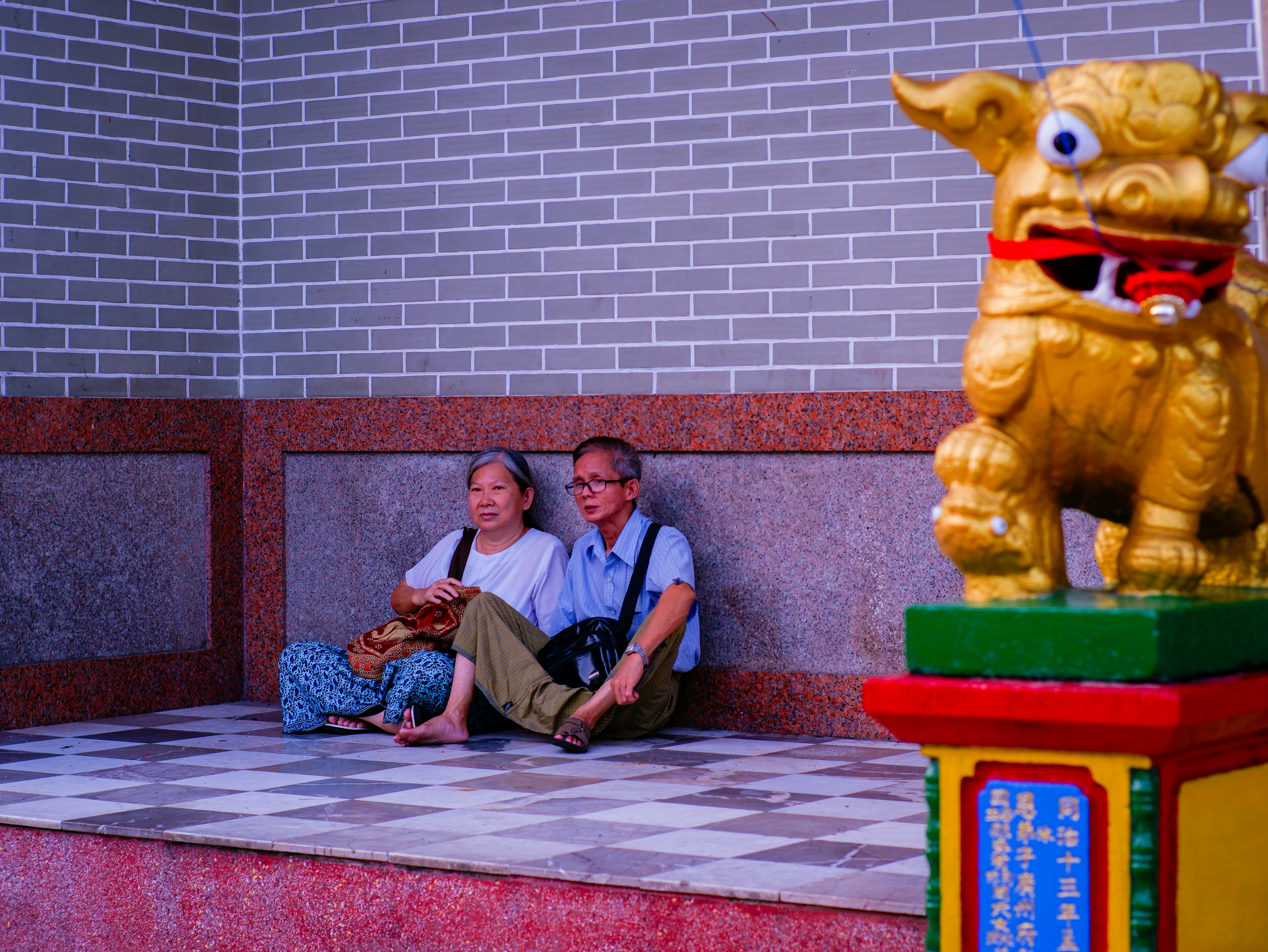 Elderly couple sitting by a golden lion statue