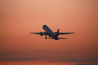 Airplane ascending against a vibrant sunset sky