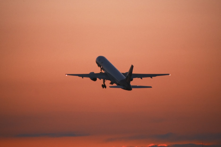 Airplane ascending against a vibrant sunset sky