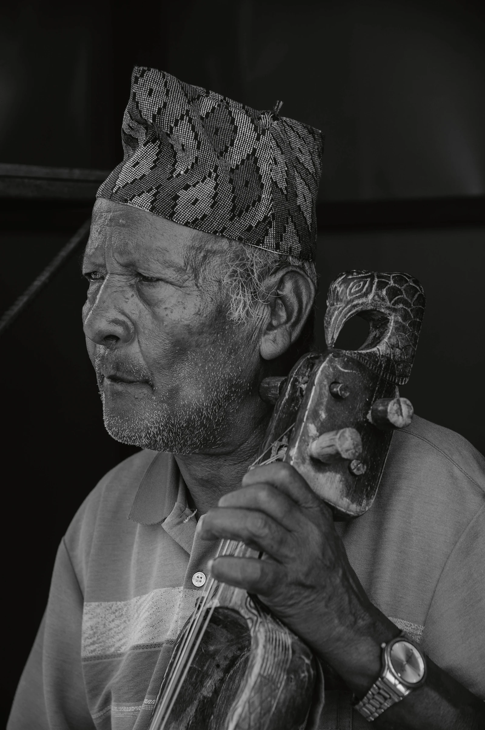 Senior musician wearing a cap, seated with a traditional instrument