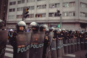 Police officers in riot gear stand in formation.