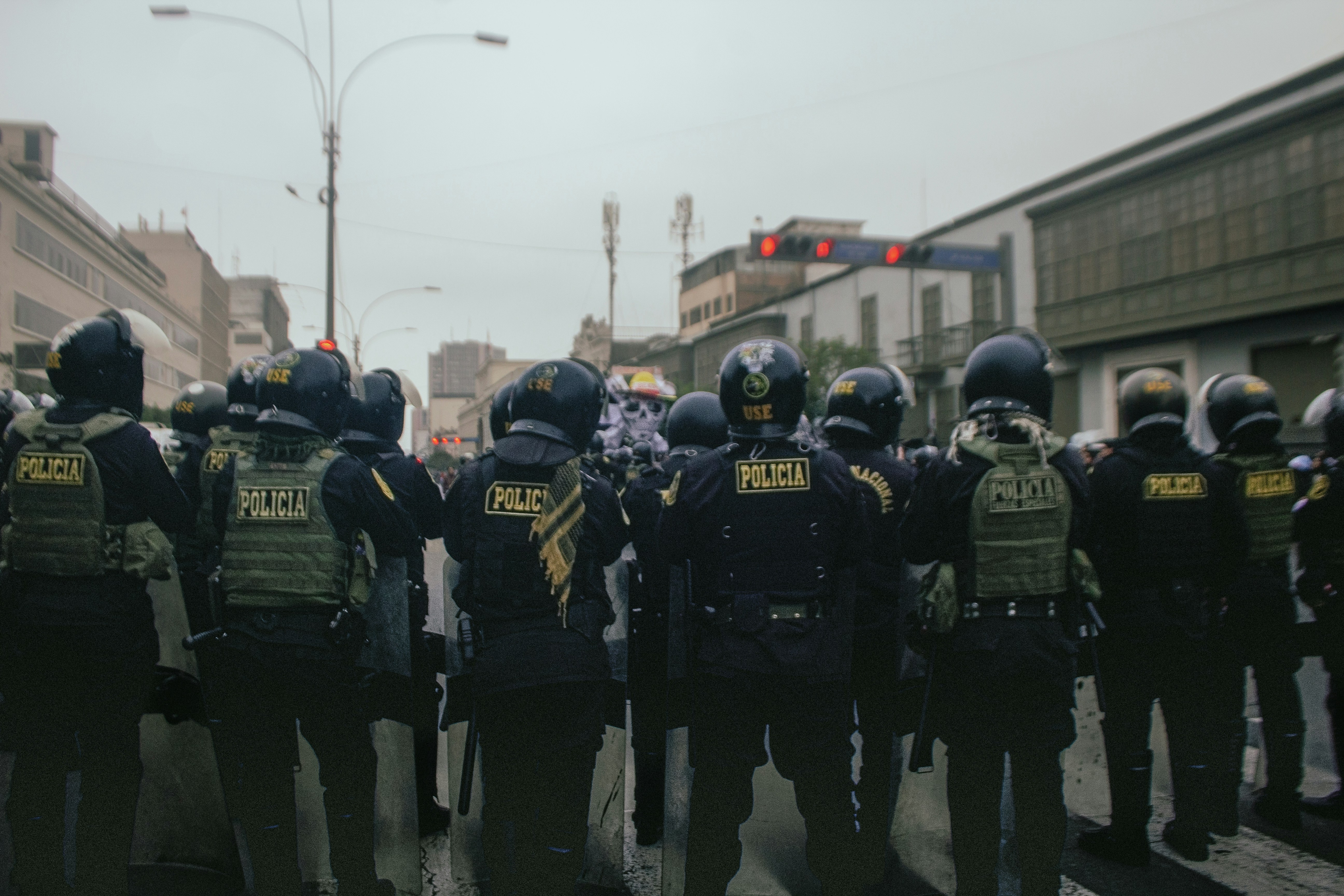 Police officers in riot gear stand on a street.