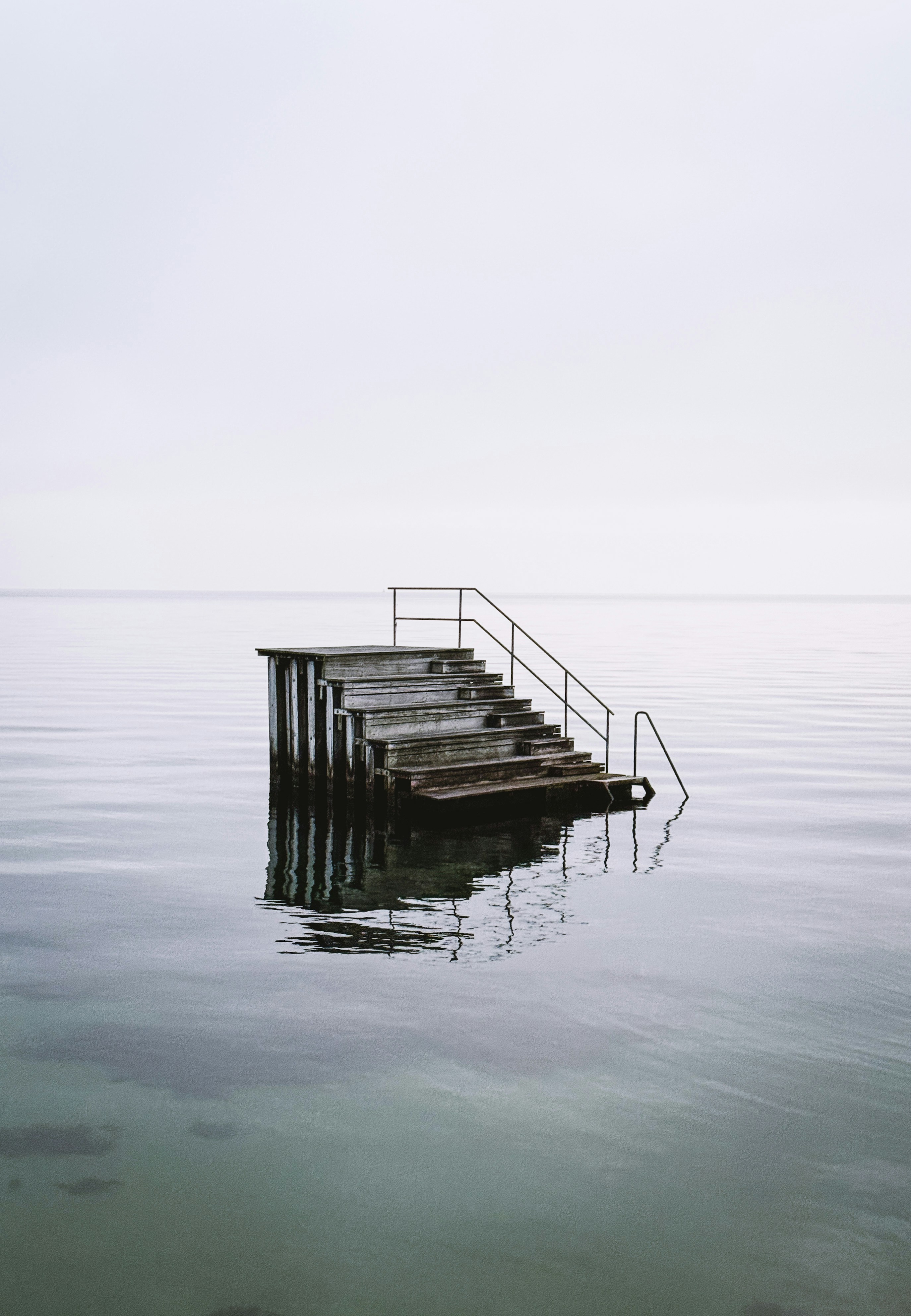 Wooden stairs leading into calm, still water.