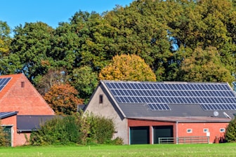 Barns with solar panels in a grassy field.