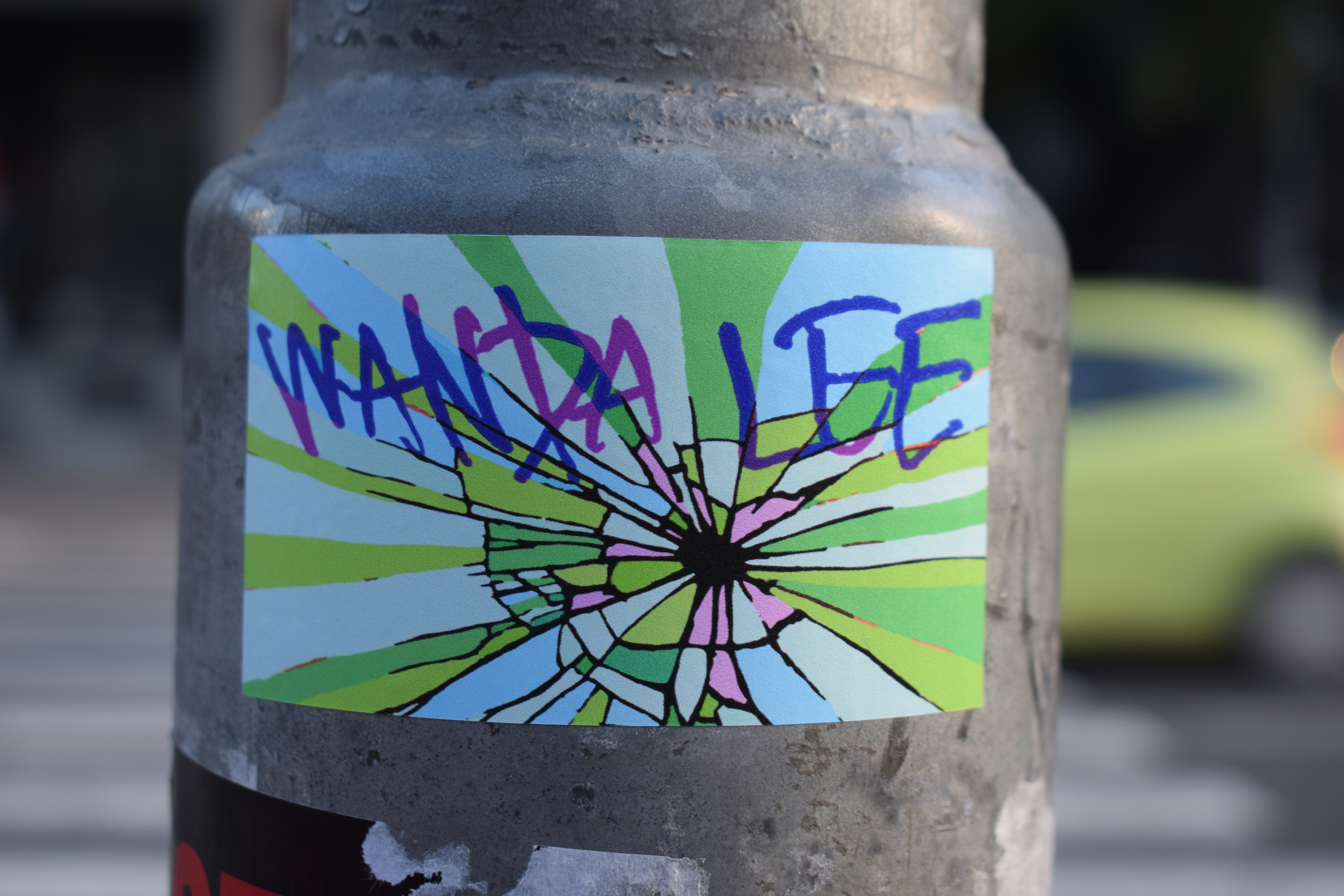 Colorful sticker with "wanda lee" text on pole.