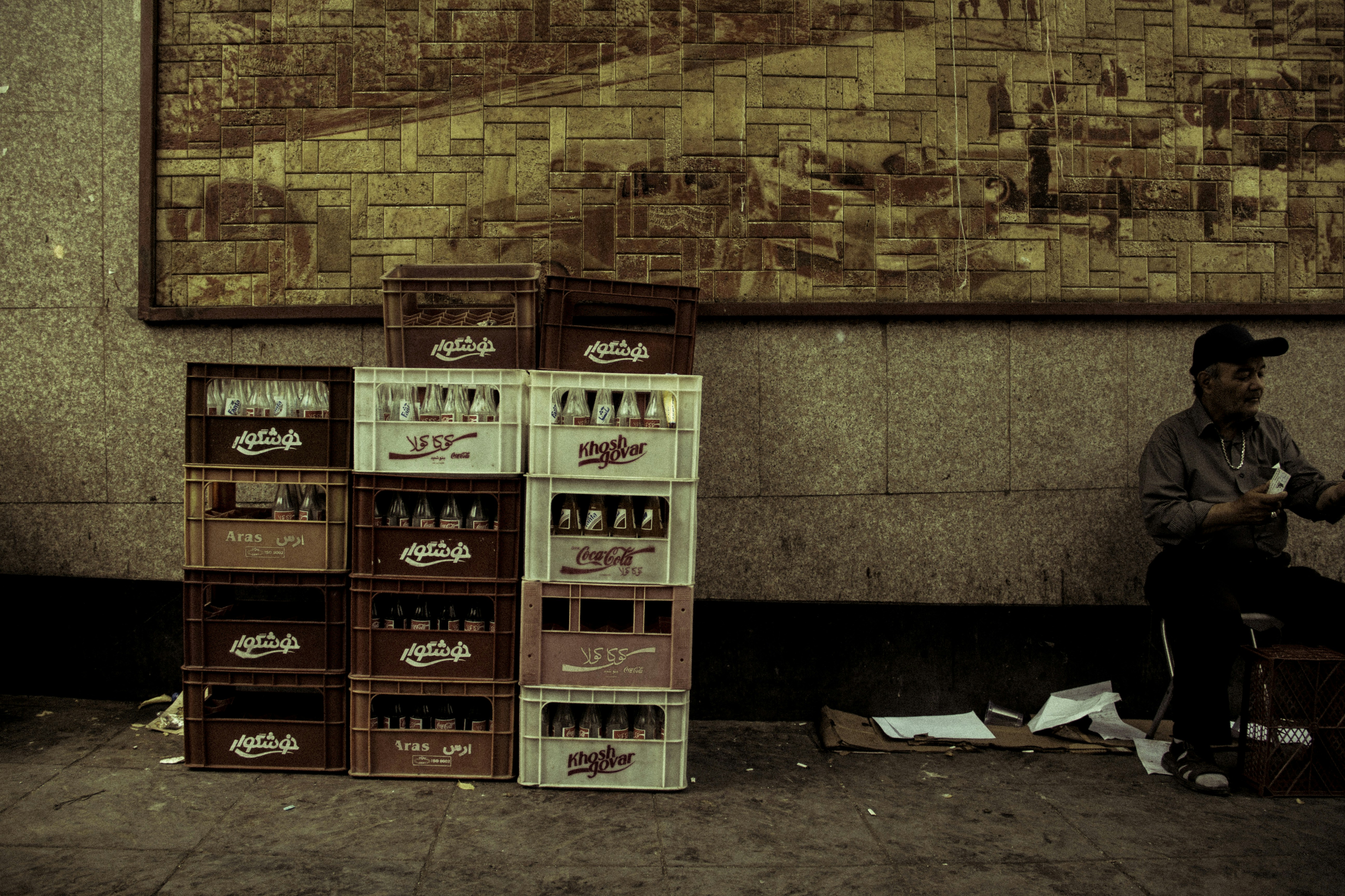 Man sitting next to stacked crates of bottles