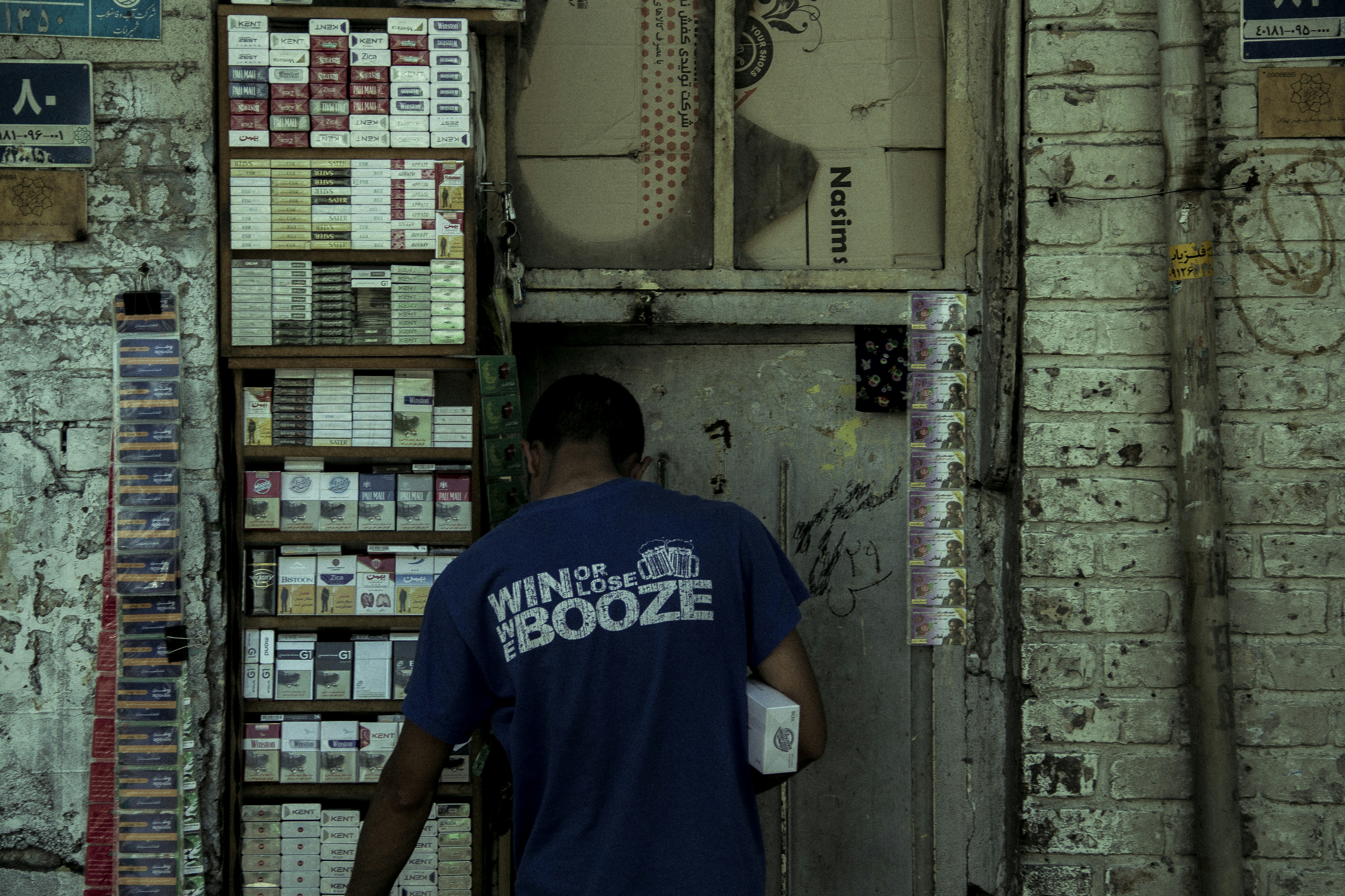 Man in blue shirt enters weathered doorway near-empty shop