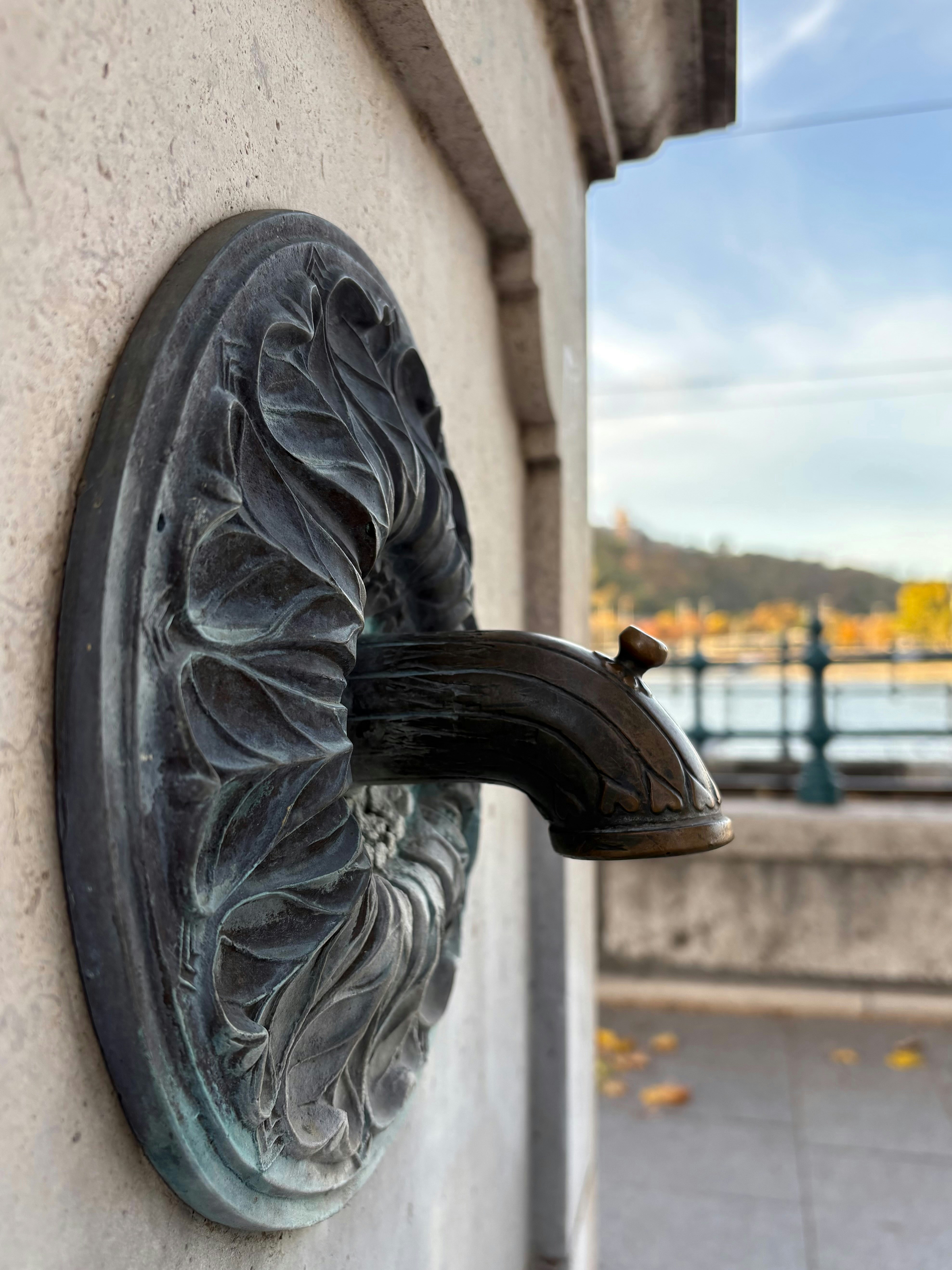 Ornate metal fountain spout on a textured wall