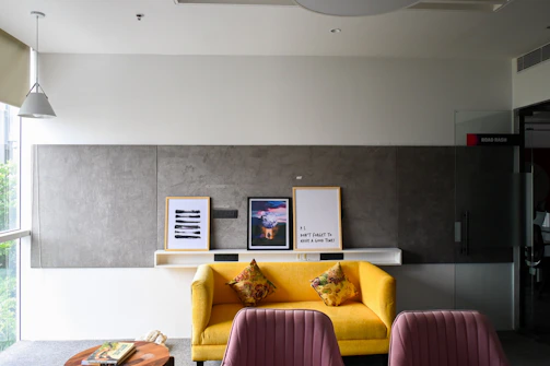 Yellow sofa with framed art above it.