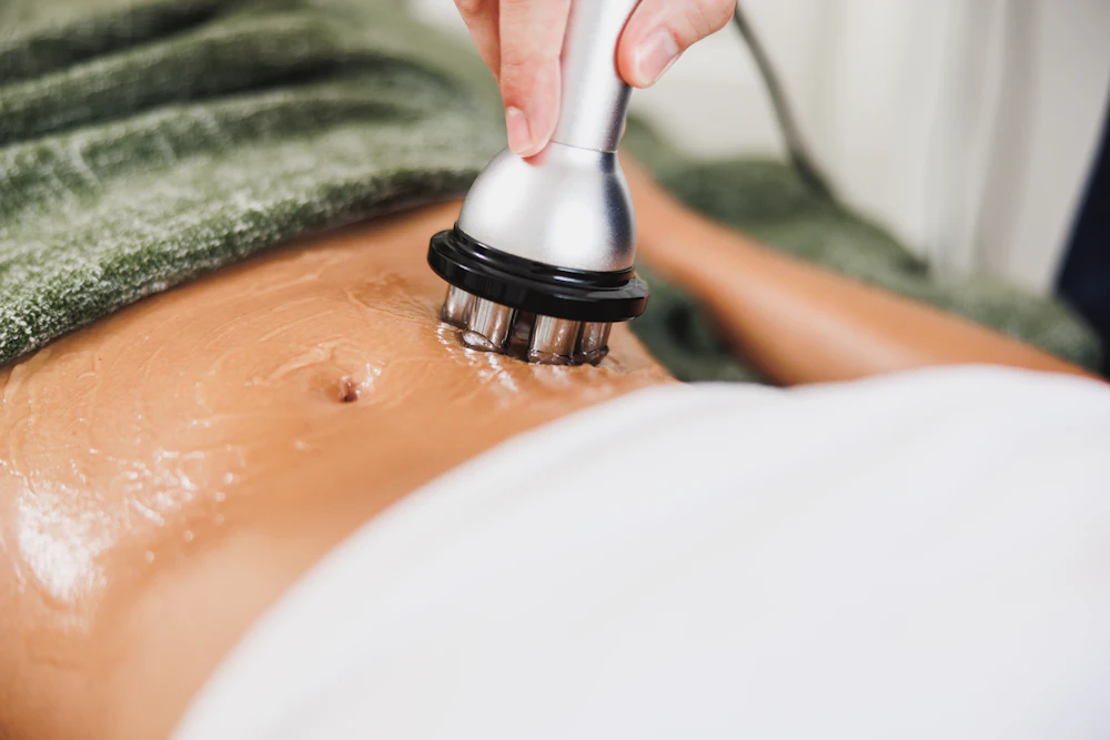 A provider gliding a handheld treatment applicator over a client's abdomen